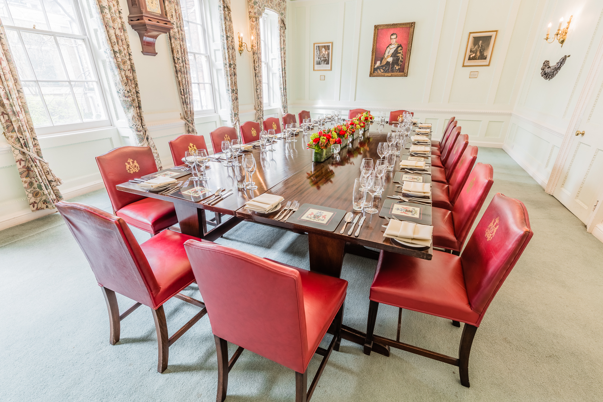 Elegant meeting room with long table, red leather chairs for corporate events.