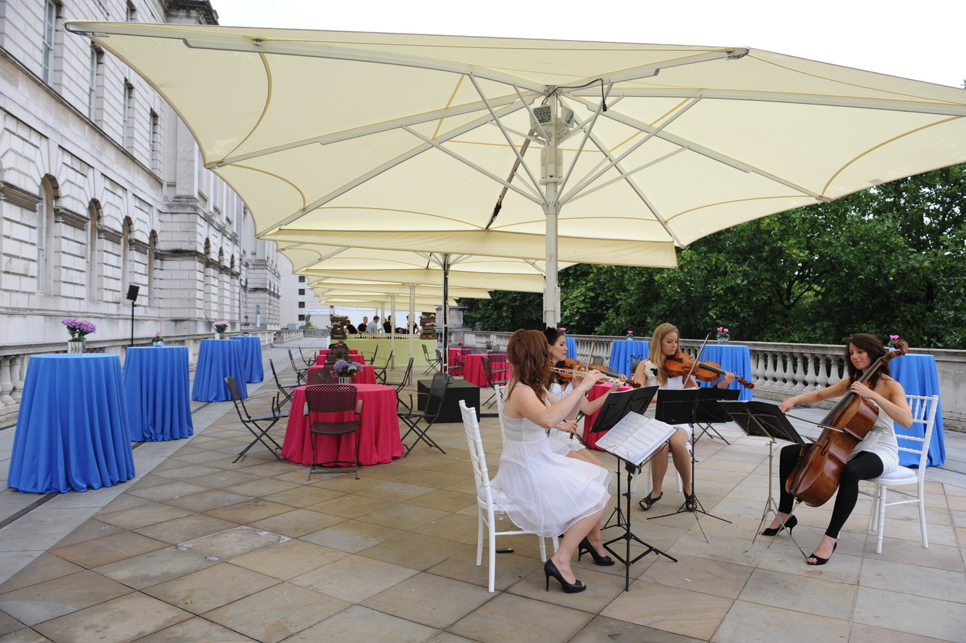 Elegant outdoor event at Somerset House with string quartet and vibrant decor.