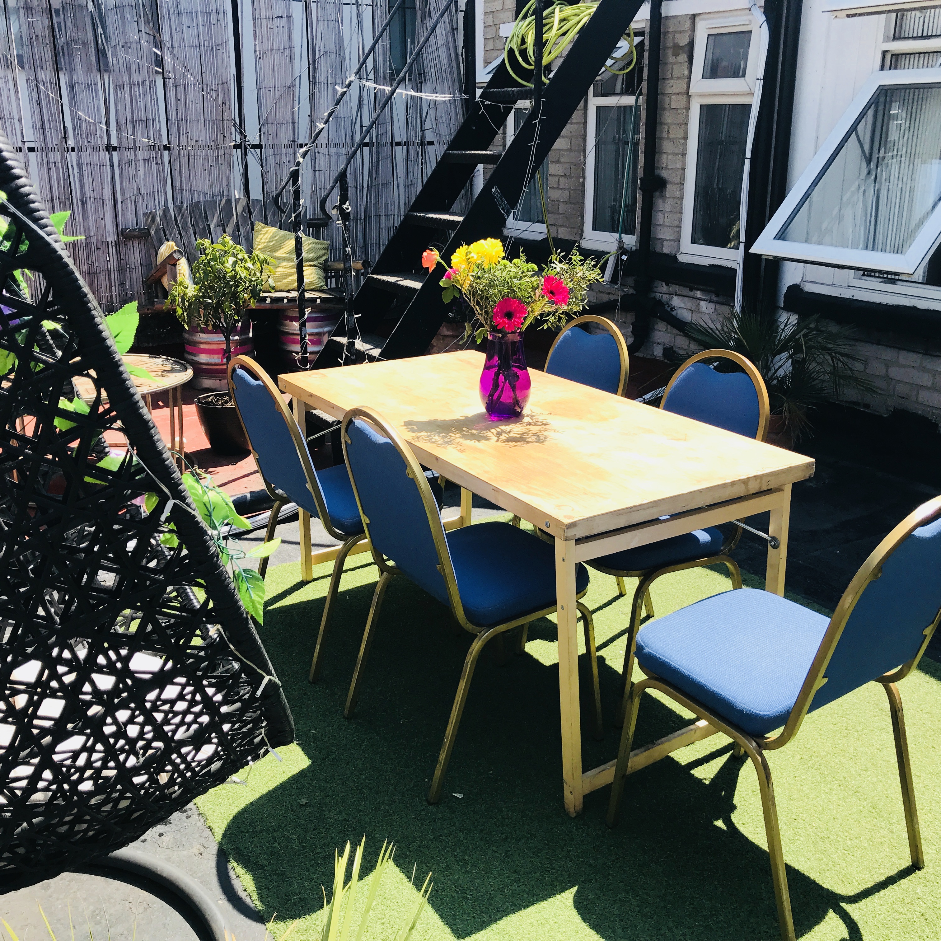 Outdoor meeting space with wooden table, blue chairs, ideal for casual gatherings.