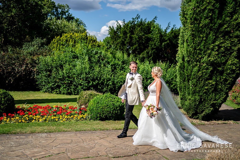 Couple walking in lush Tudor Barn Eltham garden, perfect for weddings and events.