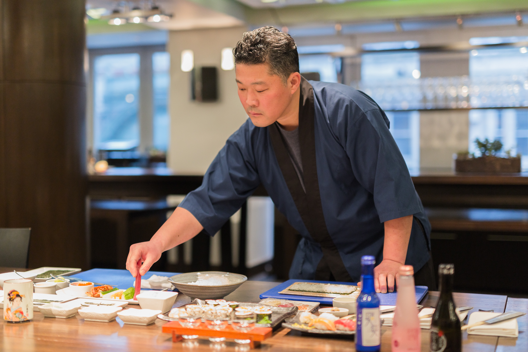 Culinary professional arranging dishes in upscale Andaz Studio dining setting for events.