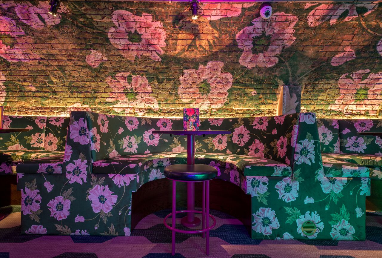 Vibrant event space at Blame Gloria with floral seating, perfect for networking events.