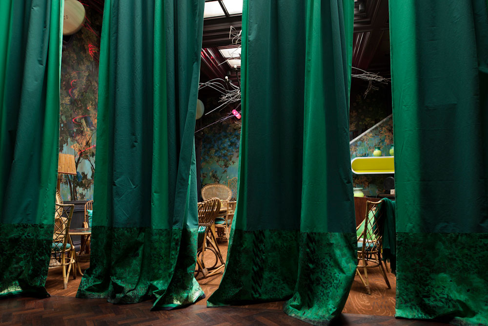 Vibrant event space with green curtains, ideal for meetings and social functions.