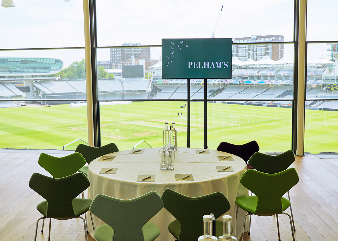 Stylish meeting setup at Lord's Cricket Ground with round table and green chairs.
