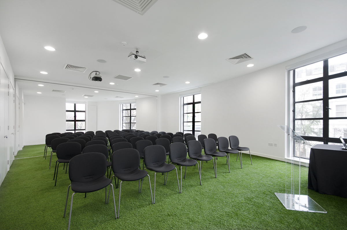 Modern conference room with green carpet, ideal for workshops and seminars.