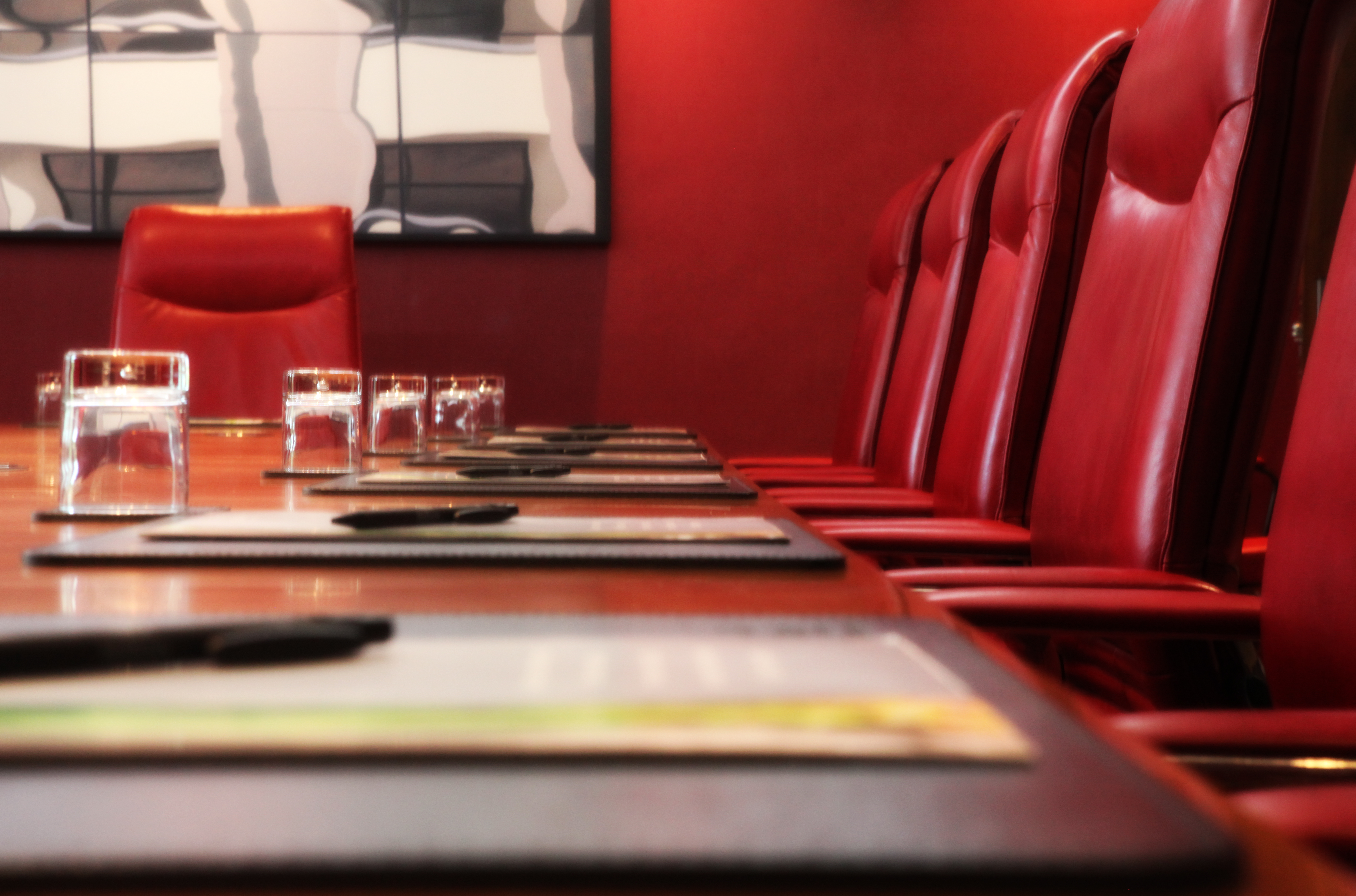 Boardroom at Hilton Liverpool: polished wooden table, red leather chairs, ideal for meetings.