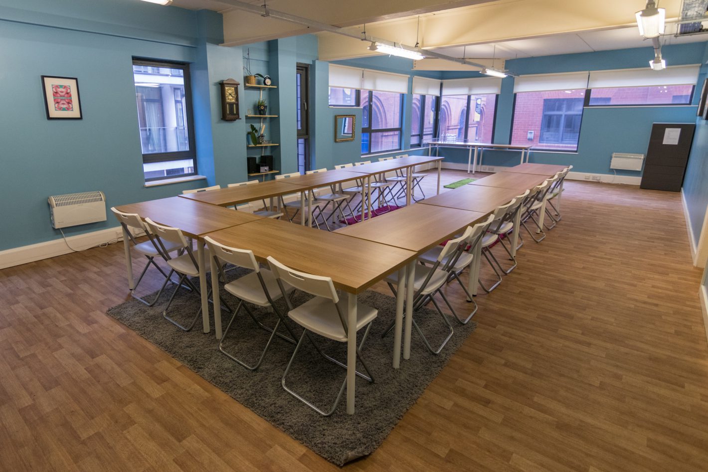 Versatile U-shaped meeting space for workshops, featuring bright walls and natural light.