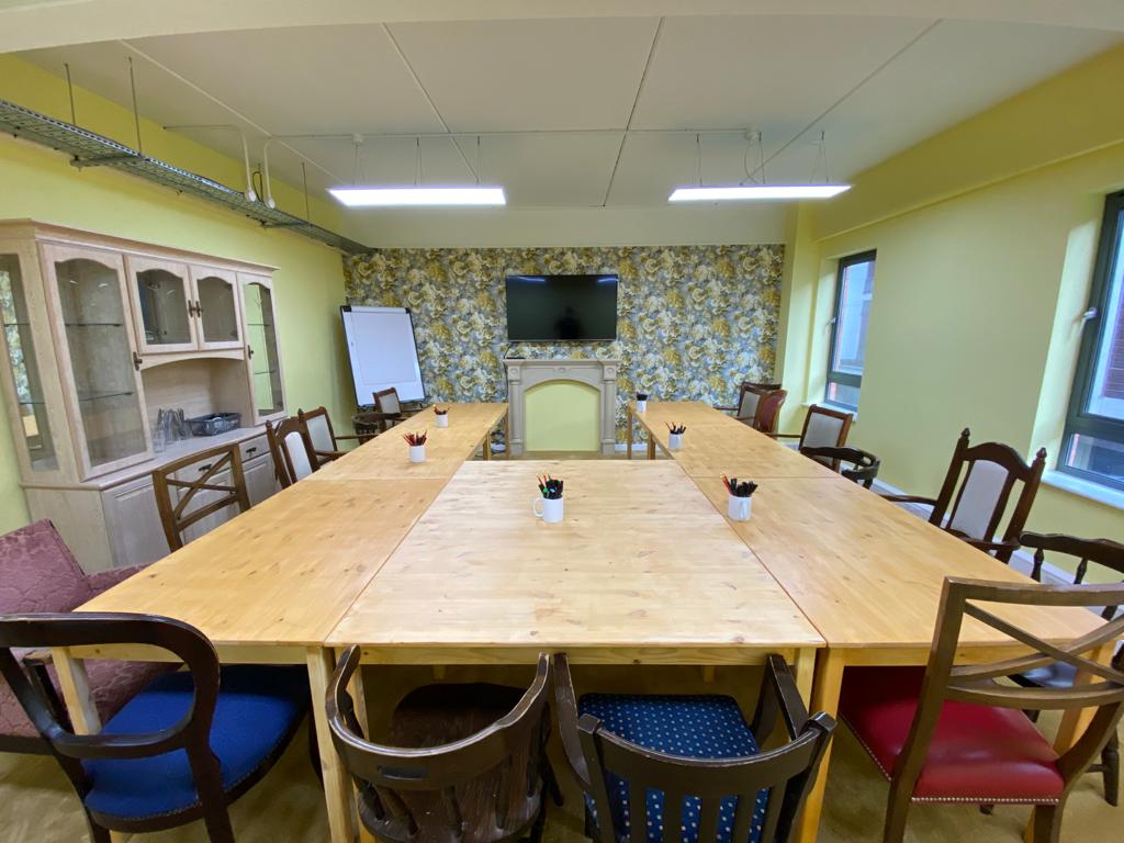 Bright meeting room with large wooden table, ideal for workshops and team meetings.