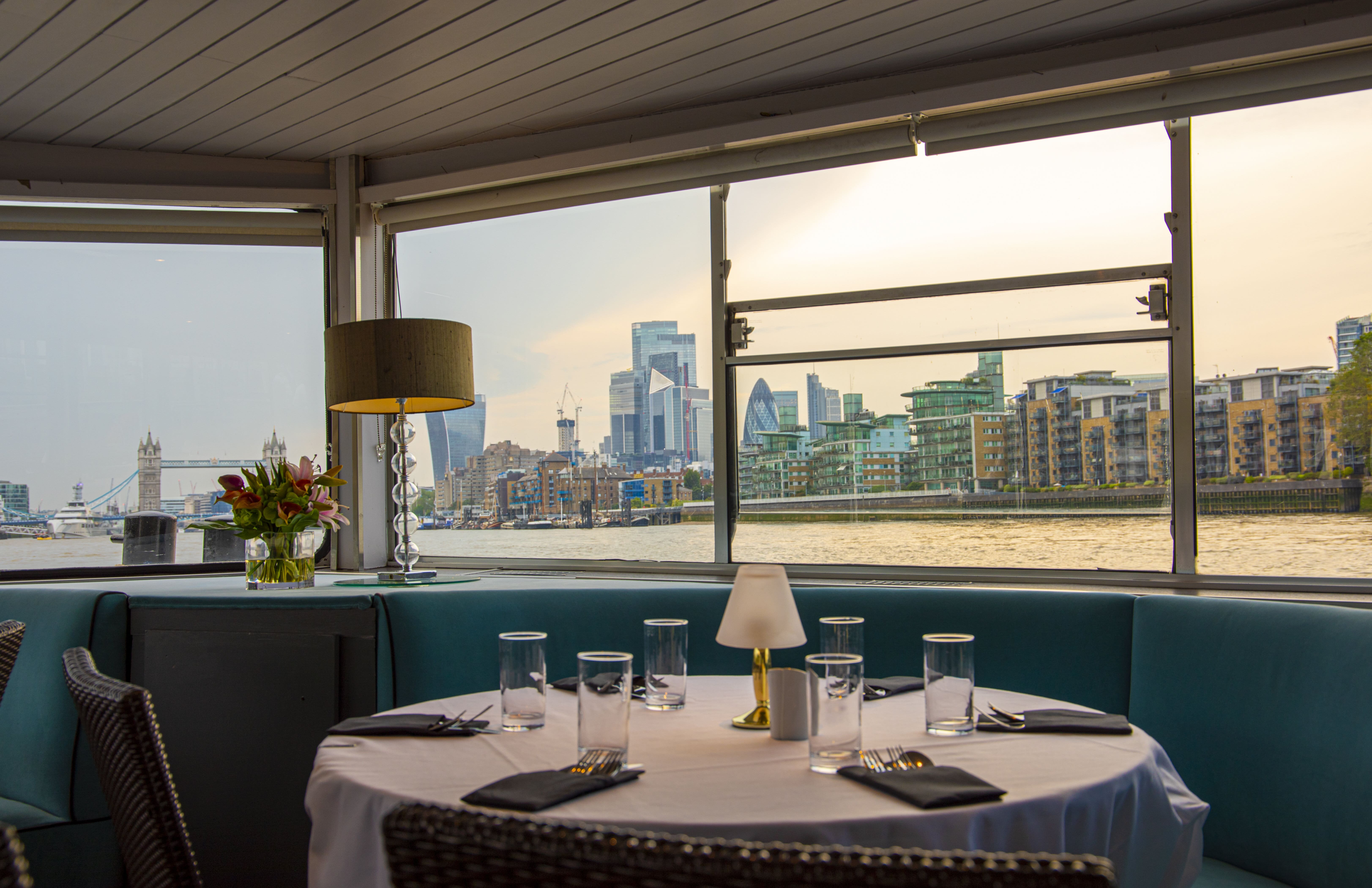 Elegant dining setup on M.V. Erasmus with London skyline, ideal for upscale events.