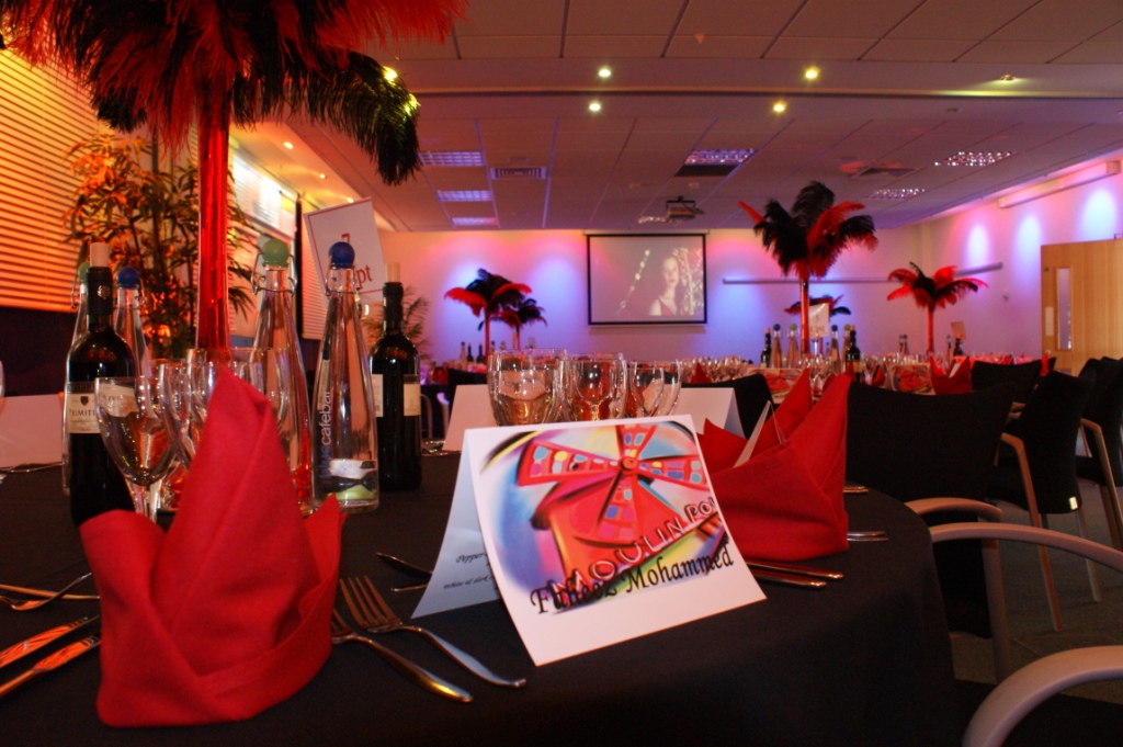 Elegant event space with black linens and red napkins for corporate gatherings.