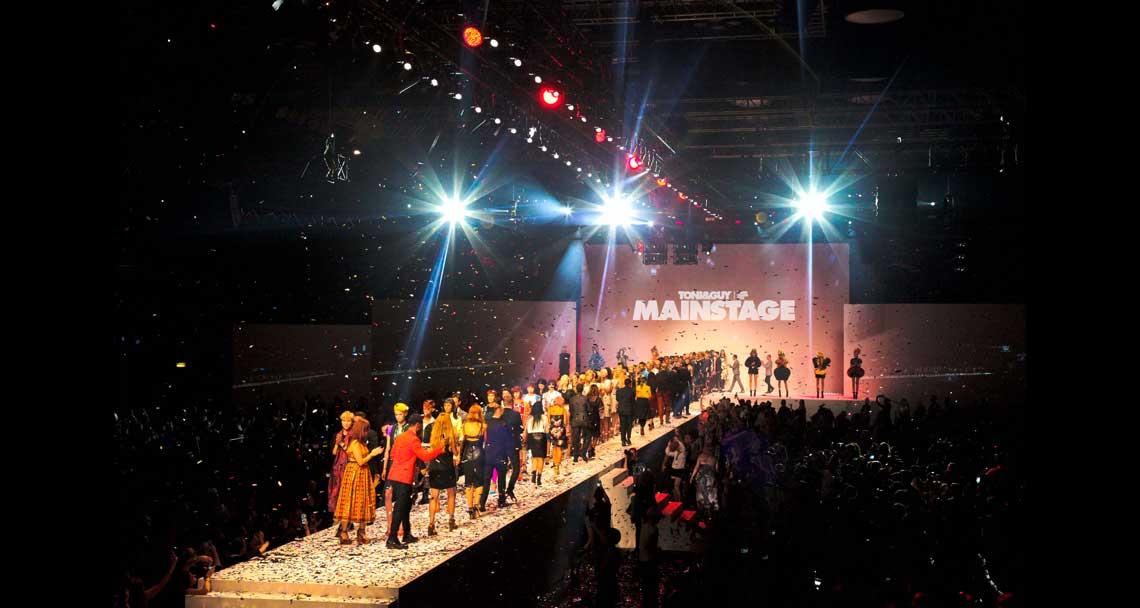 Vibrant fashion runway at Copper Box Arena with diverse models and dynamic lighting.