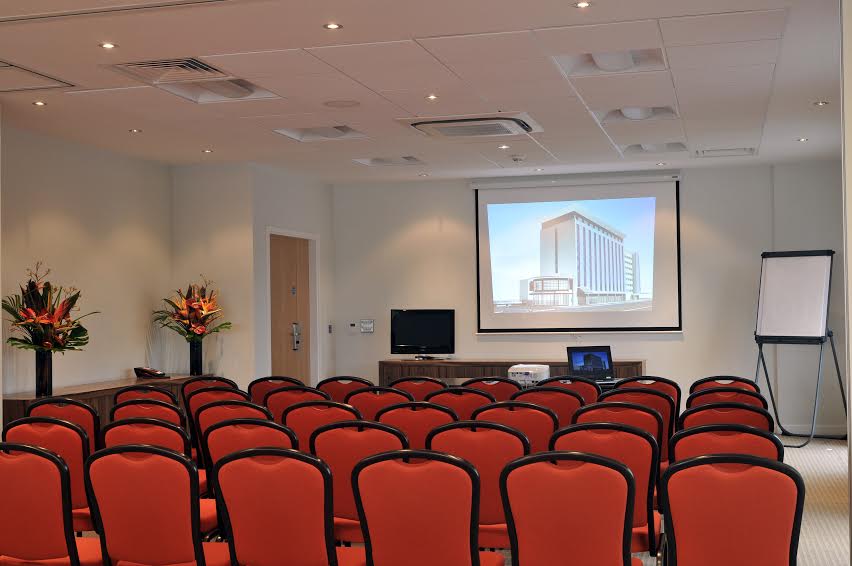 Cinnamon Suite meeting room with red chairs, ideal for corporate events and presentations.