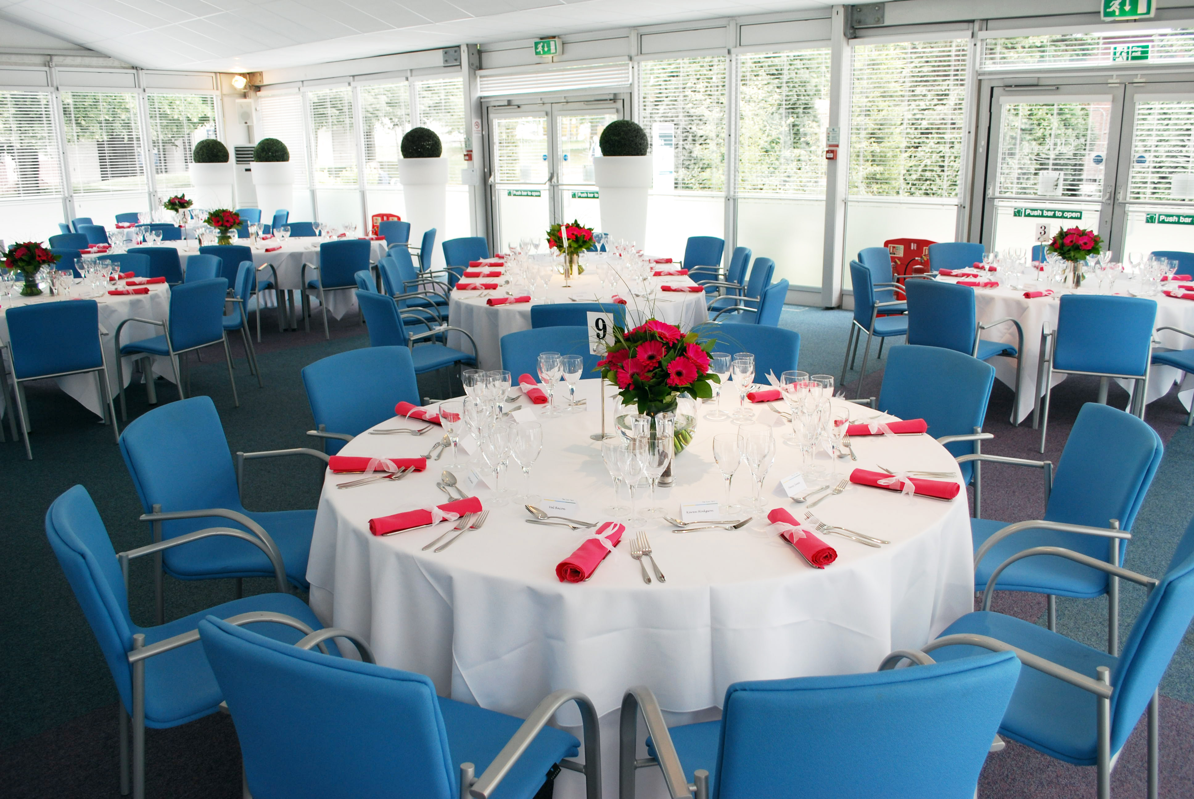 Elegant event space at The Ark Conference Centre with floral centerpieces and bright blue chairs.