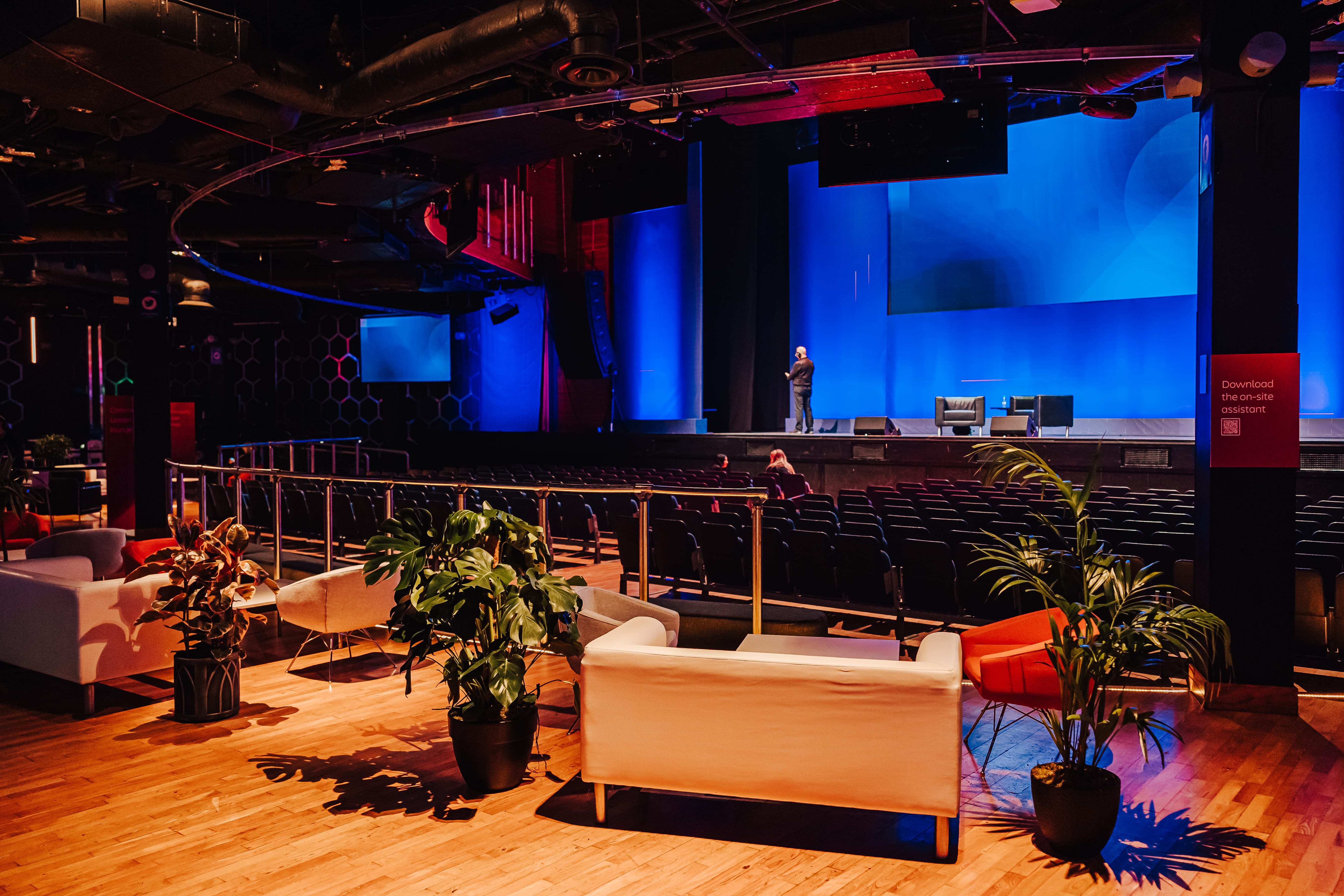 Spacious event venue at The O2, featuring blue lighting for presentations and networking.