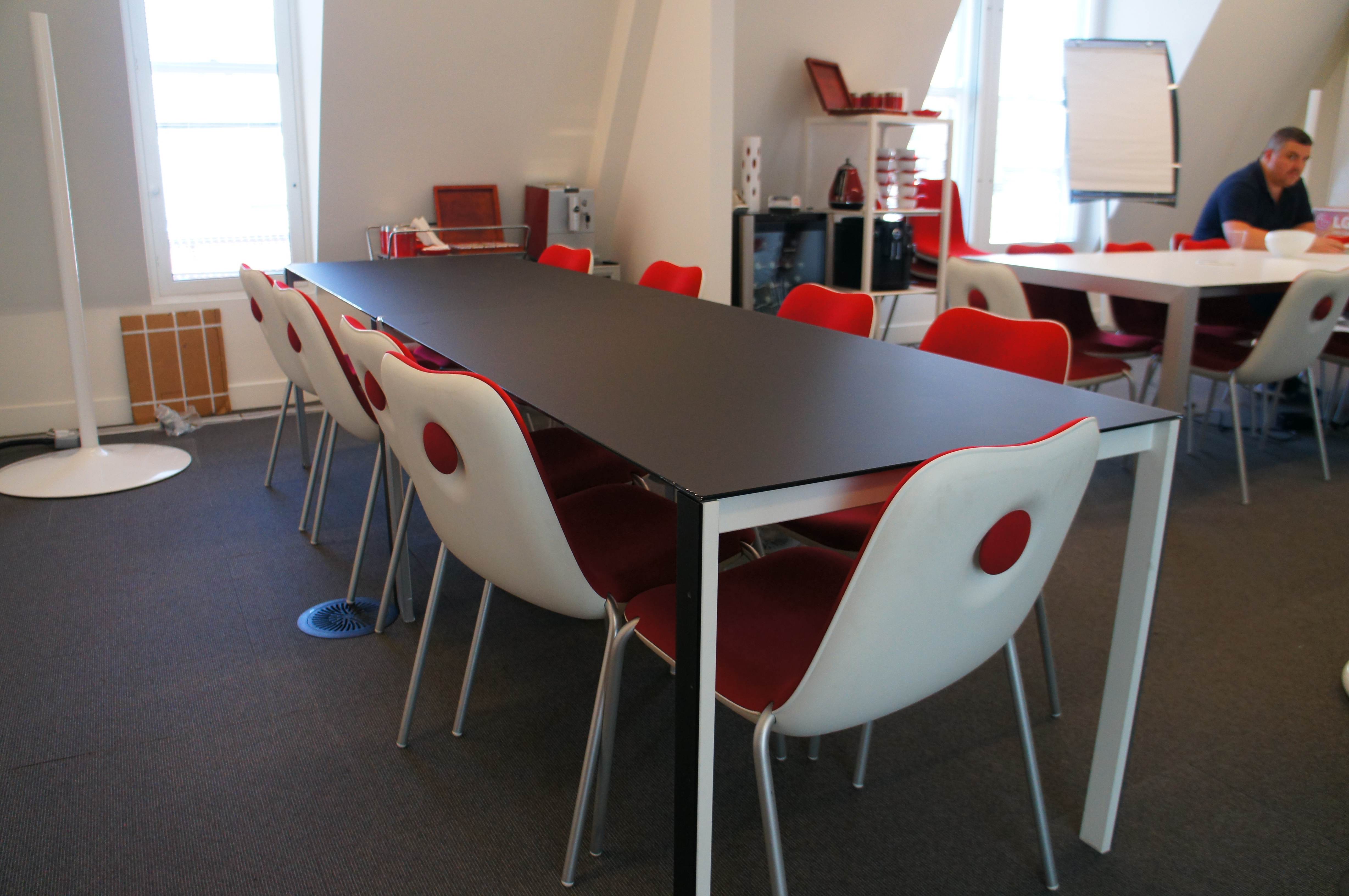 Modern conference room with black table and red chairs, ideal for meetings and brainstorming.