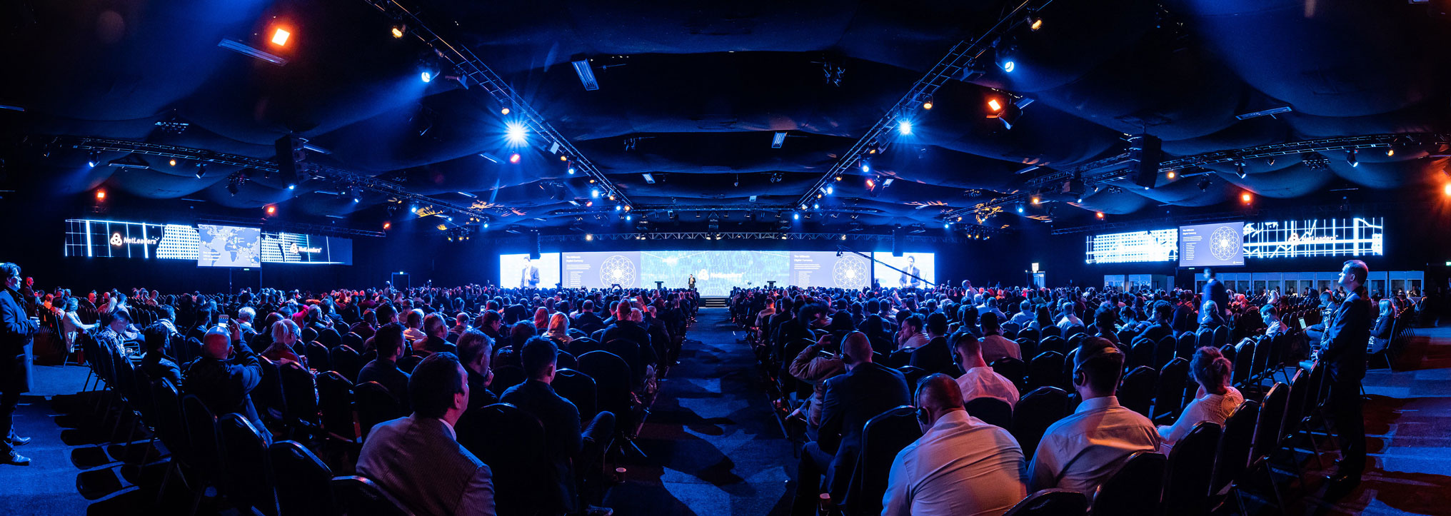 Large conference venue in Evolution London with vibrant blue stage lighting.