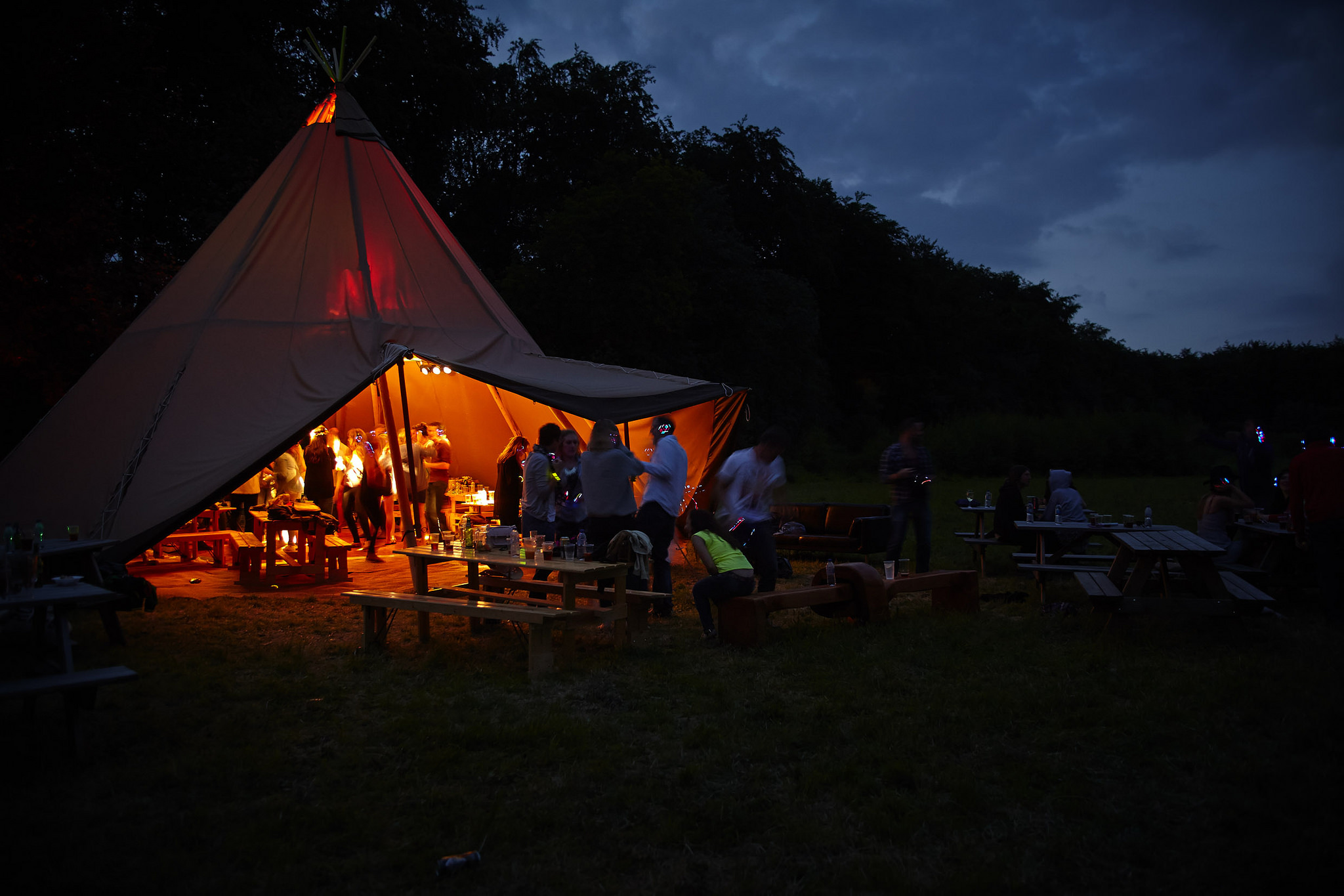 Forest Tepee event in Forest of Dean, warm-lit tent with rustic seating for gatherings.