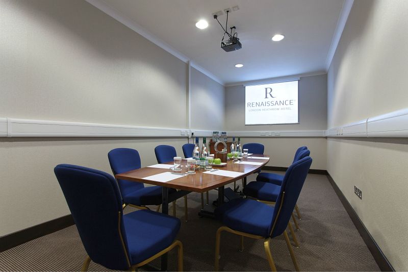 Lobby Room 2 at Renaissance London Heathrow Hotel, featuring a central table and projector for meetings.