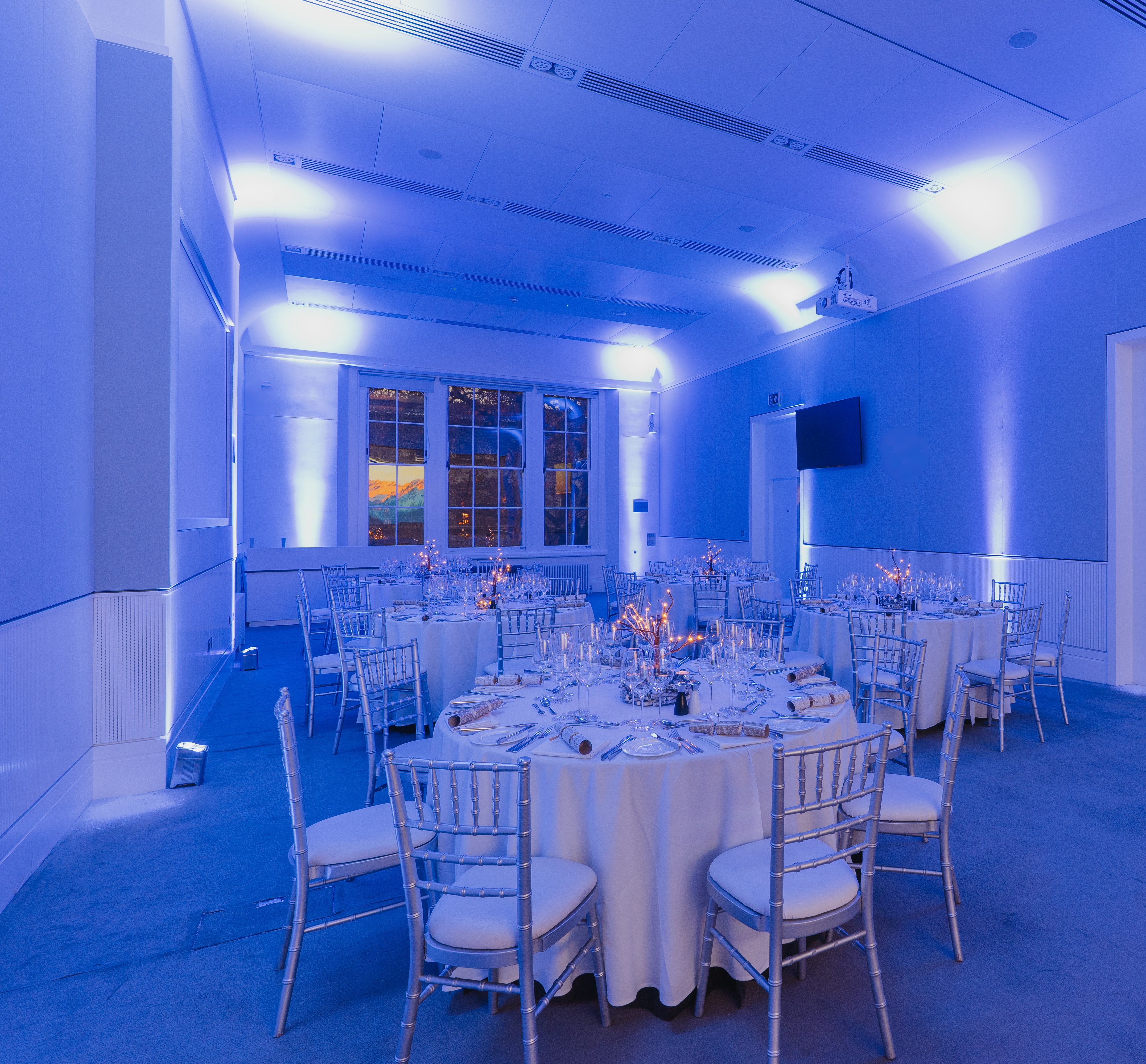 Elegant event space at Prince Philip House with round tables and blue lighting.