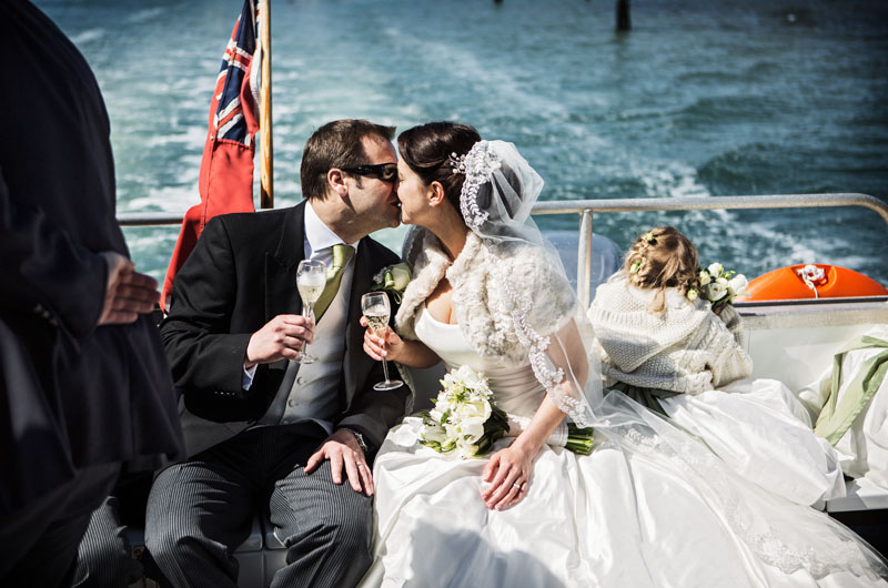 Couple celebrating wedding in elegant Ward Room, No Man's Fort, with scenic backdrop.