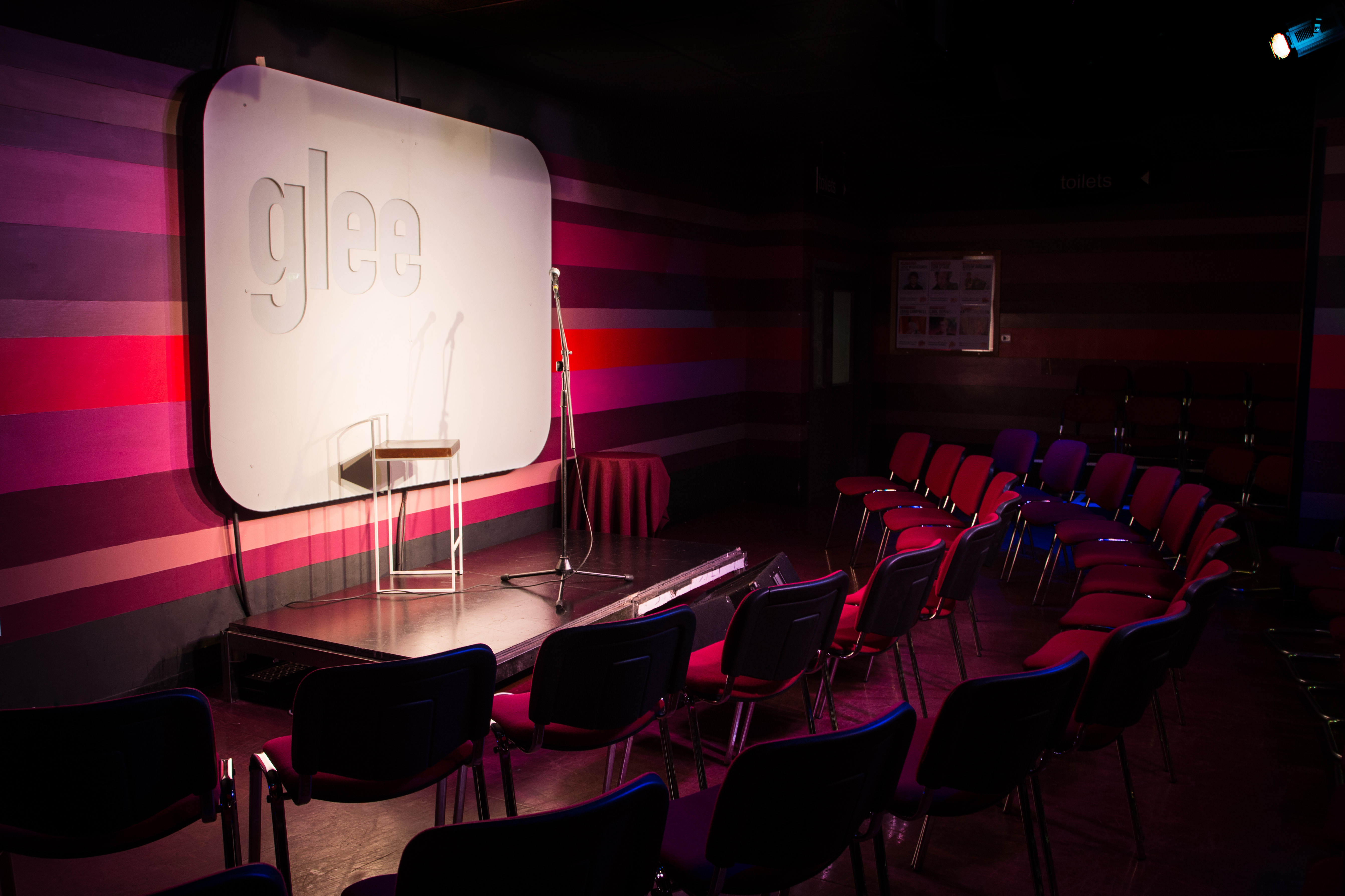Intimate event space in Glee Club Birmingham with colorful backdrop for performances and workshops.