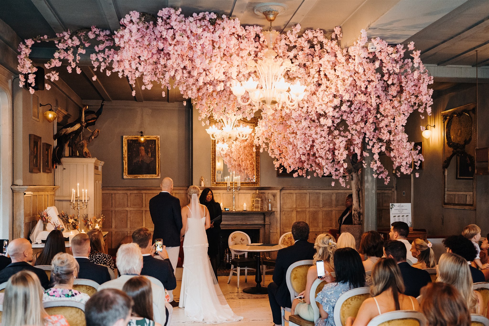 Elegant wedding ceremony with pink cherry blossoms in a cozy dining room setting.