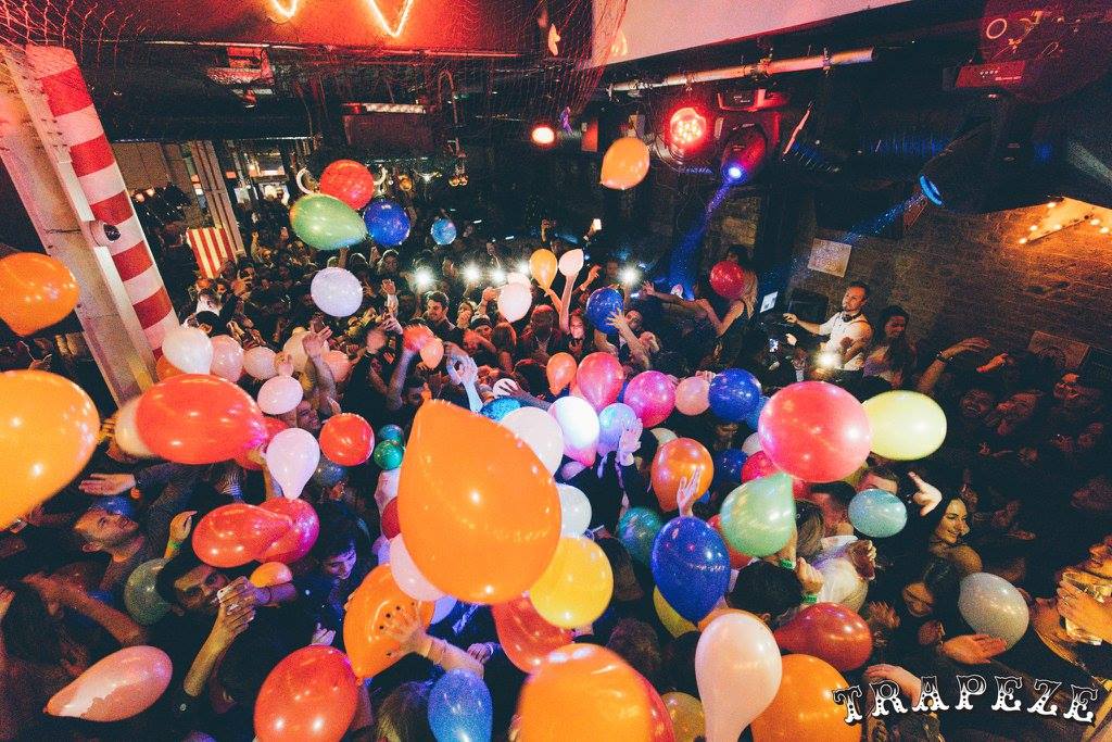 Vibrant party atmosphere at The Main Bar with colorful balloons and lively crowd.