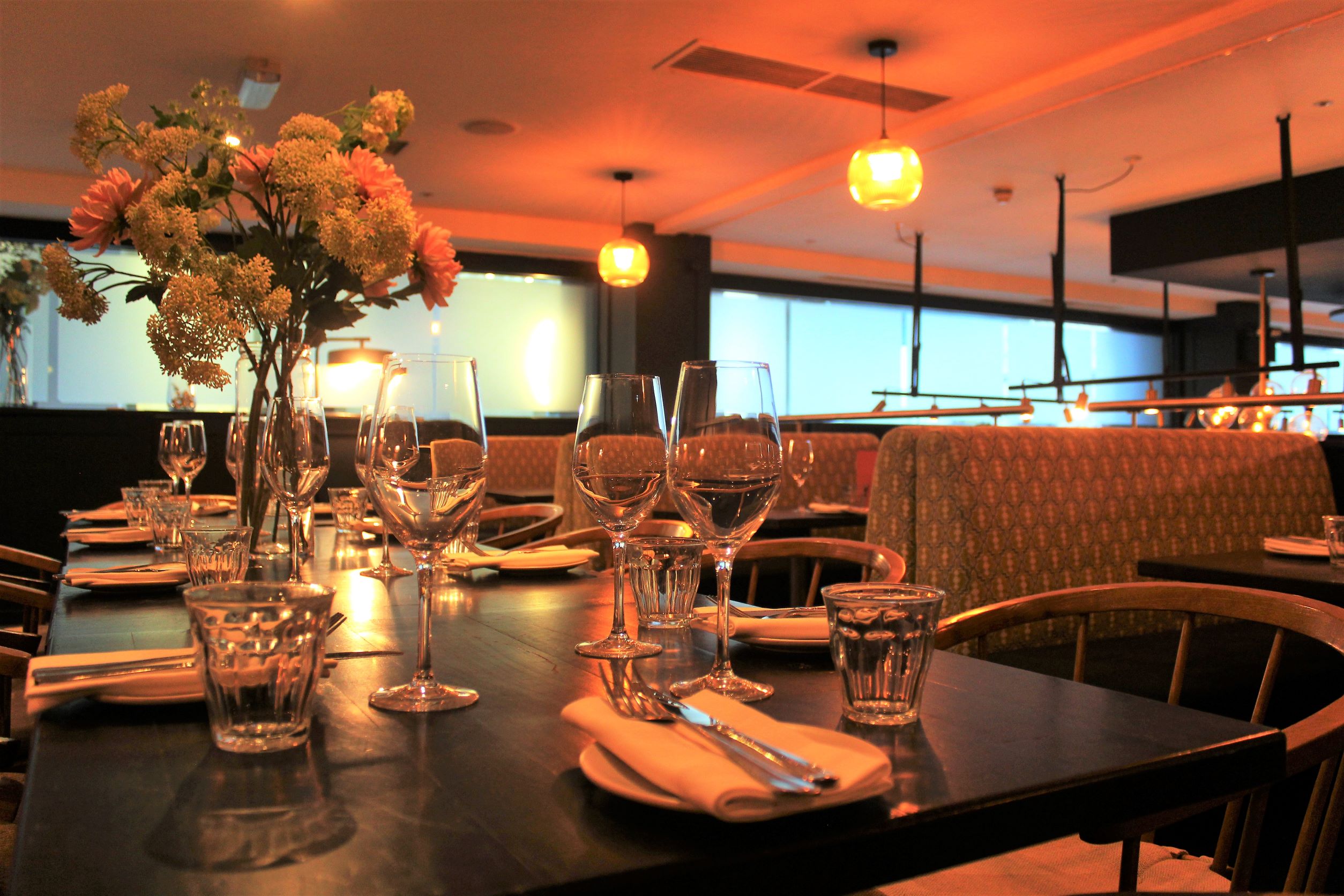 Semi-private dining table with floral centerpieces at Brasserie Blanc for corporate events.