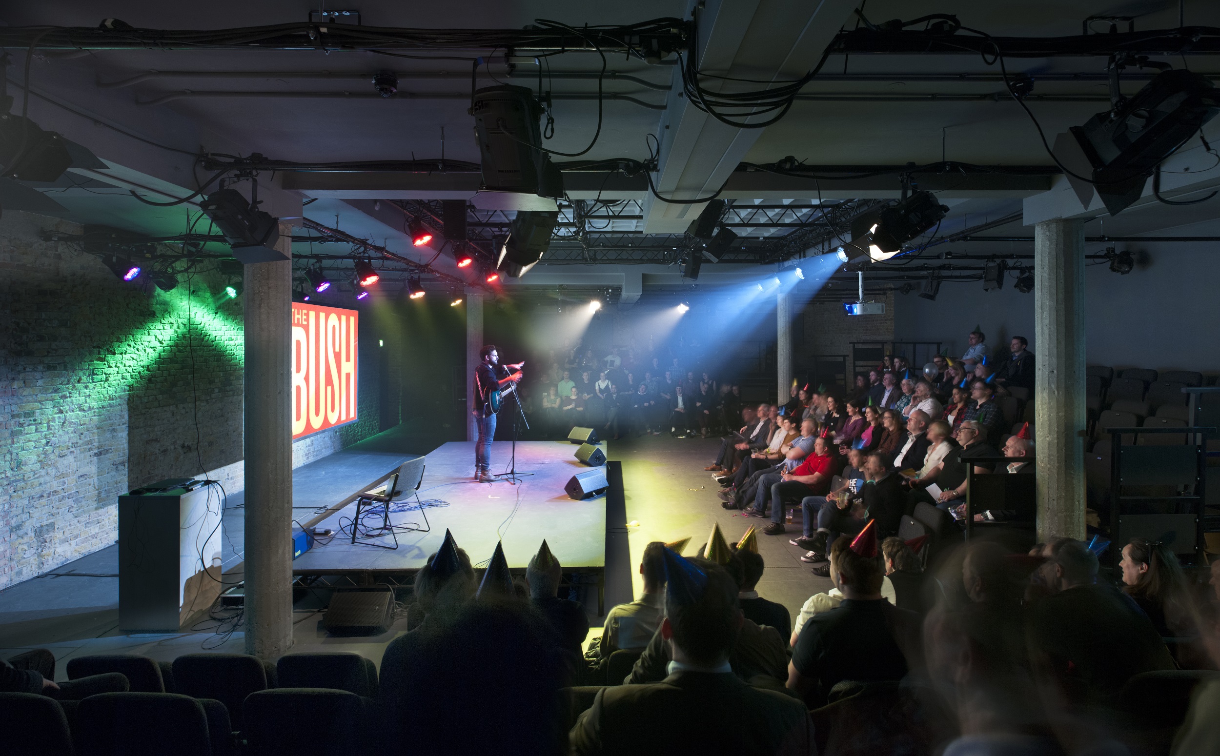 Bush Theatre auditorium with speaker engaging audience at a colorful conference event.