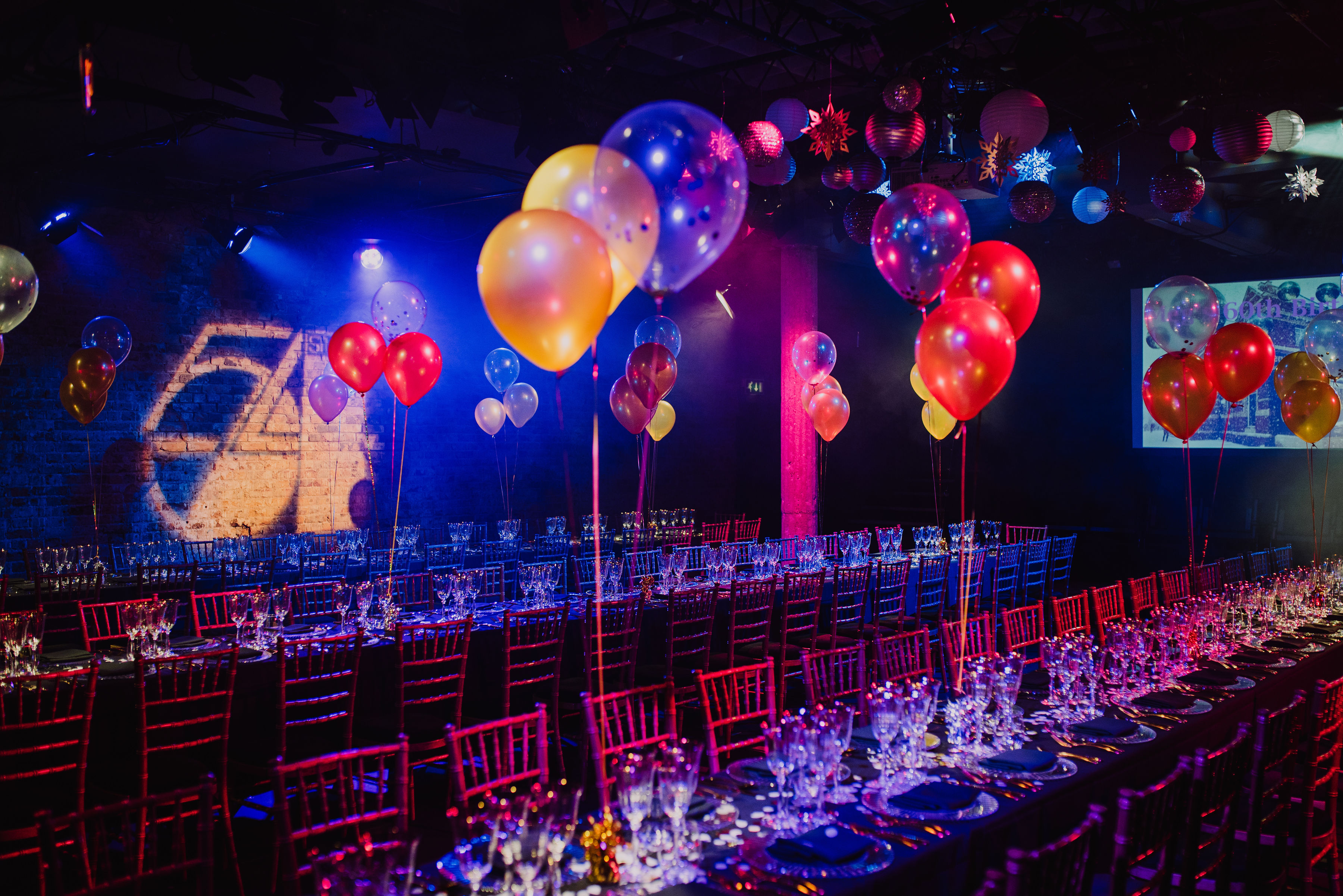 Bush Theatre auditorium set for a vibrant celebration with elegant tables and colorful balloons.