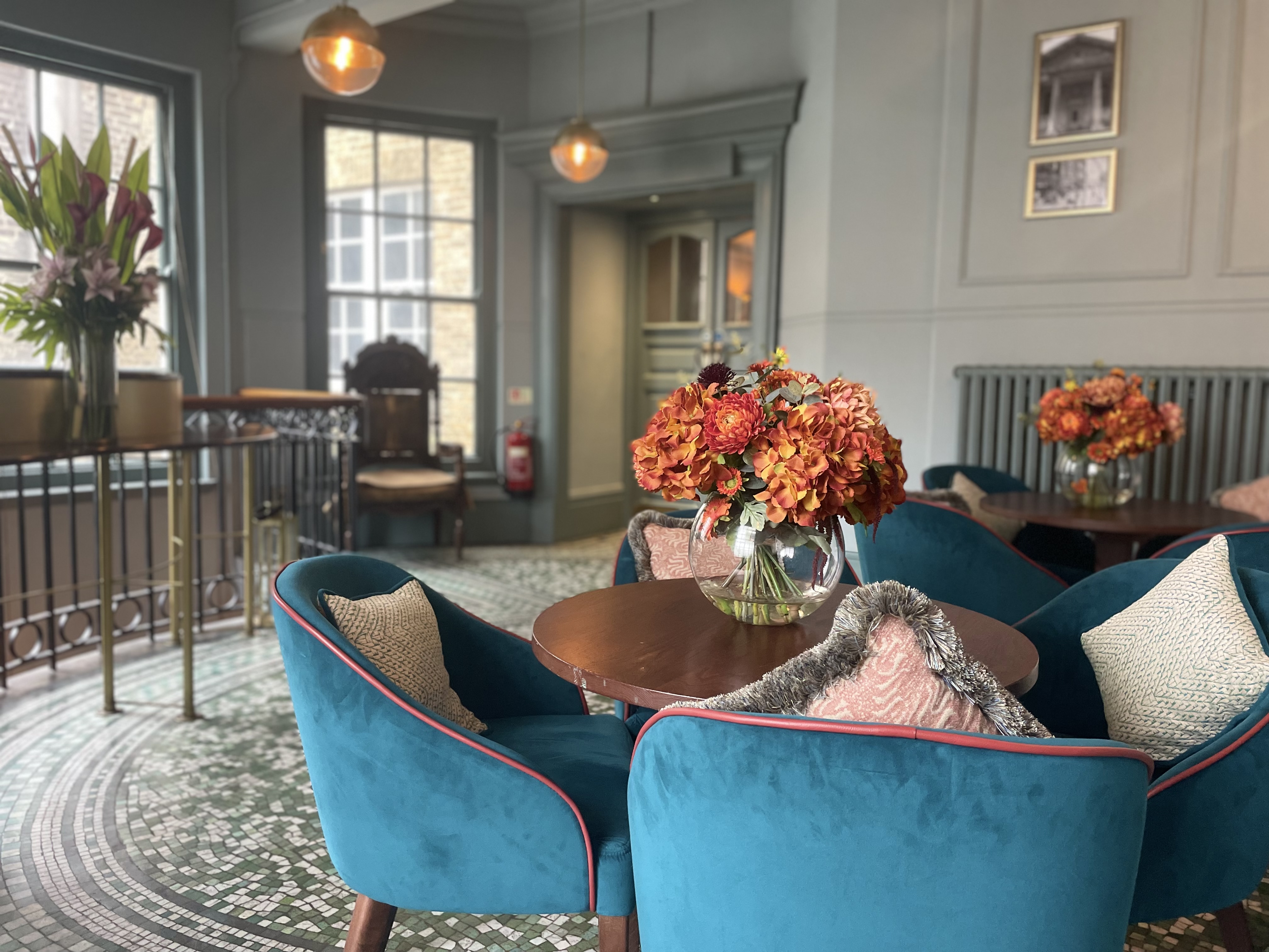 Stylish meeting space in Covent Garden with plush teal seating and floral decor.