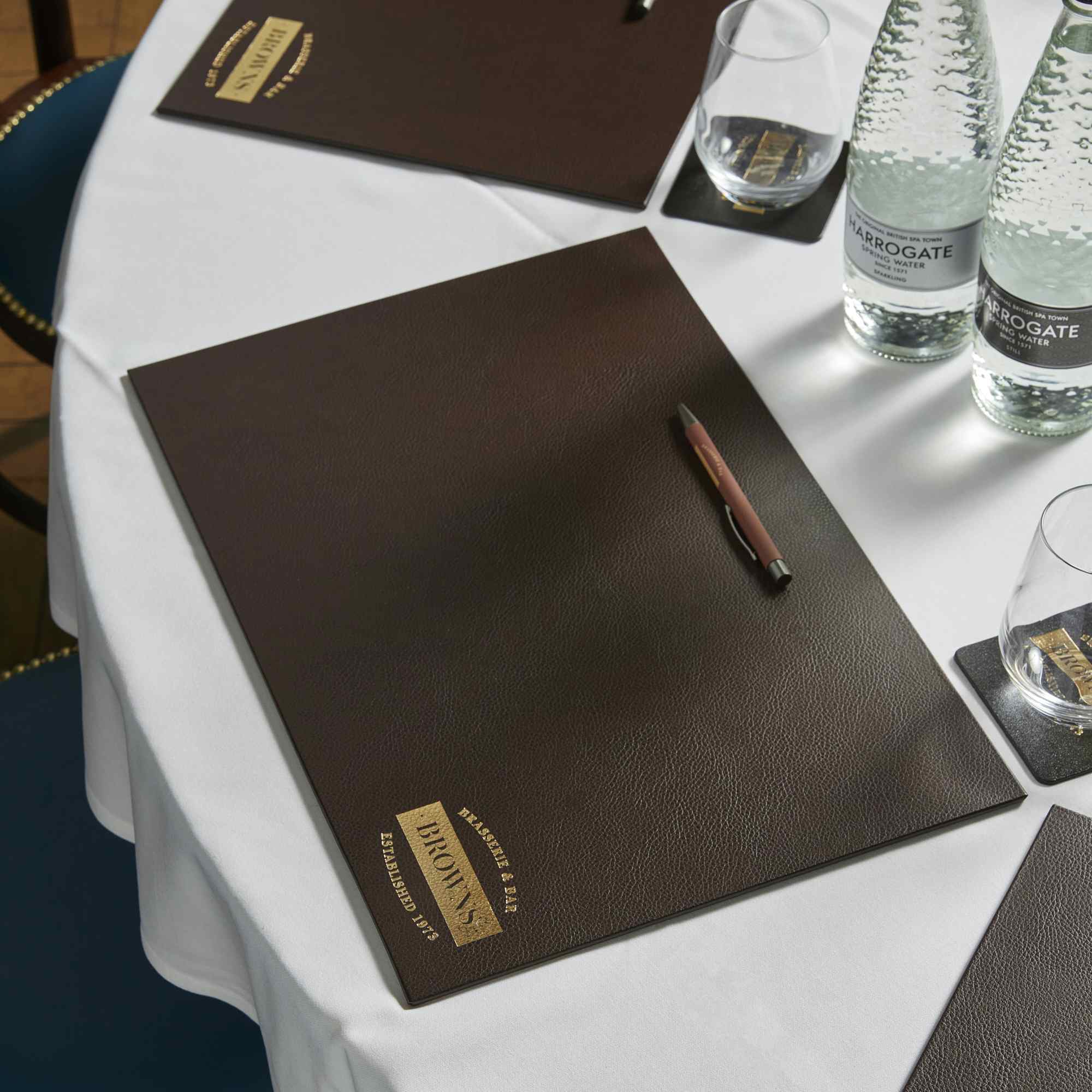 Polished meeting setup with leather folder on white tablecloth in upscale Covent Garden venue.