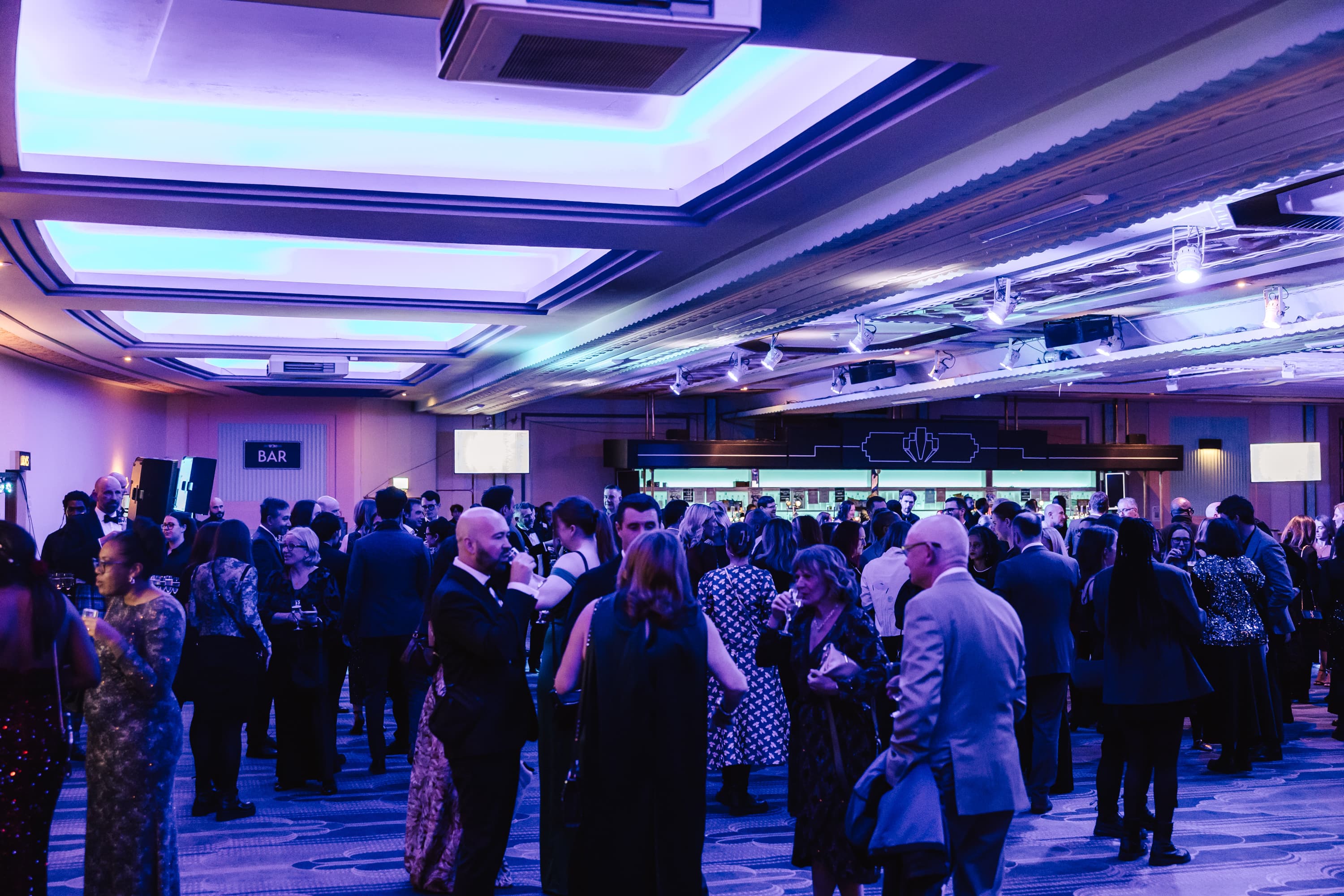 Networking reception at The Grand Hall, Troxy featuring a branded bar for corporate events.