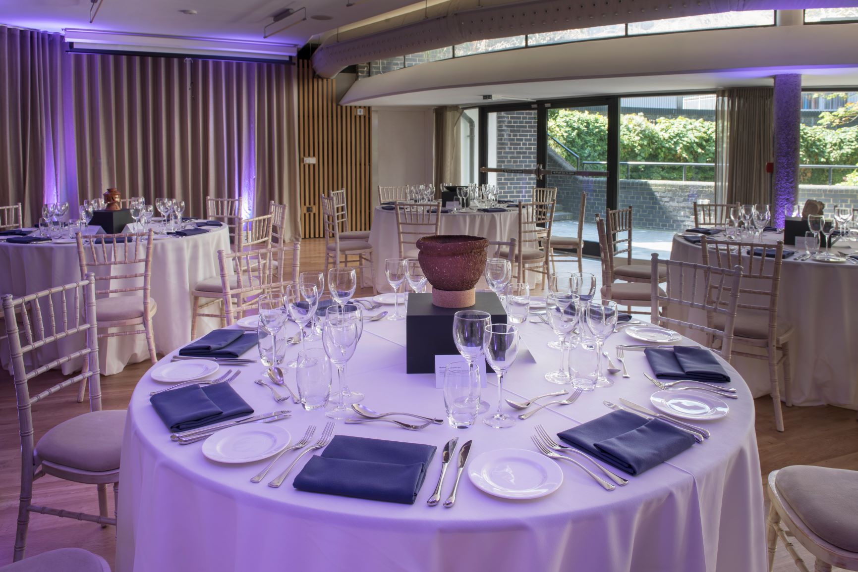 Elegant Garden Room in London Museum, set for formal events with navy accents and greenery.