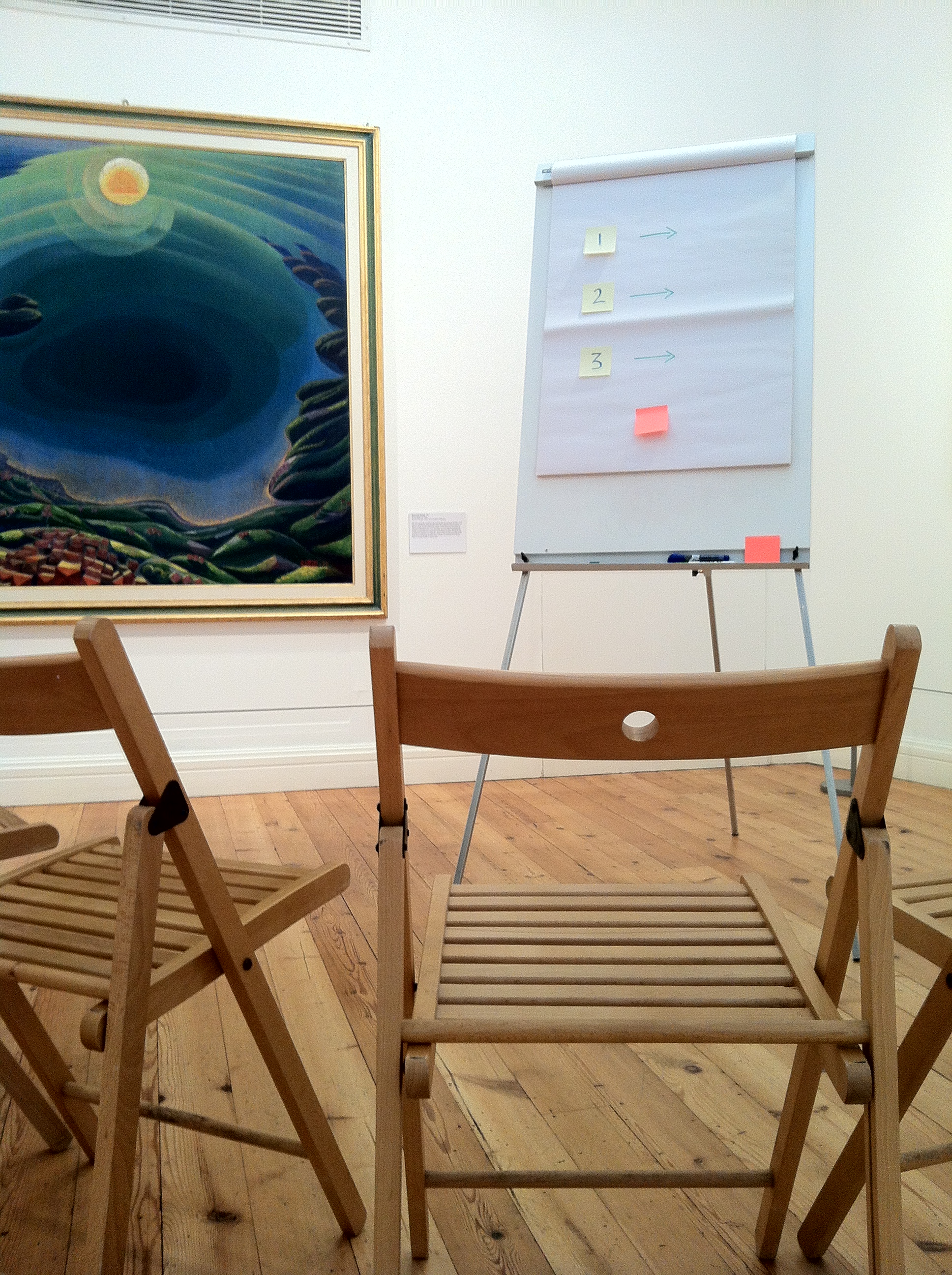 Minimalist meeting setup with wooden chairs in Estorick Collection art gallery.