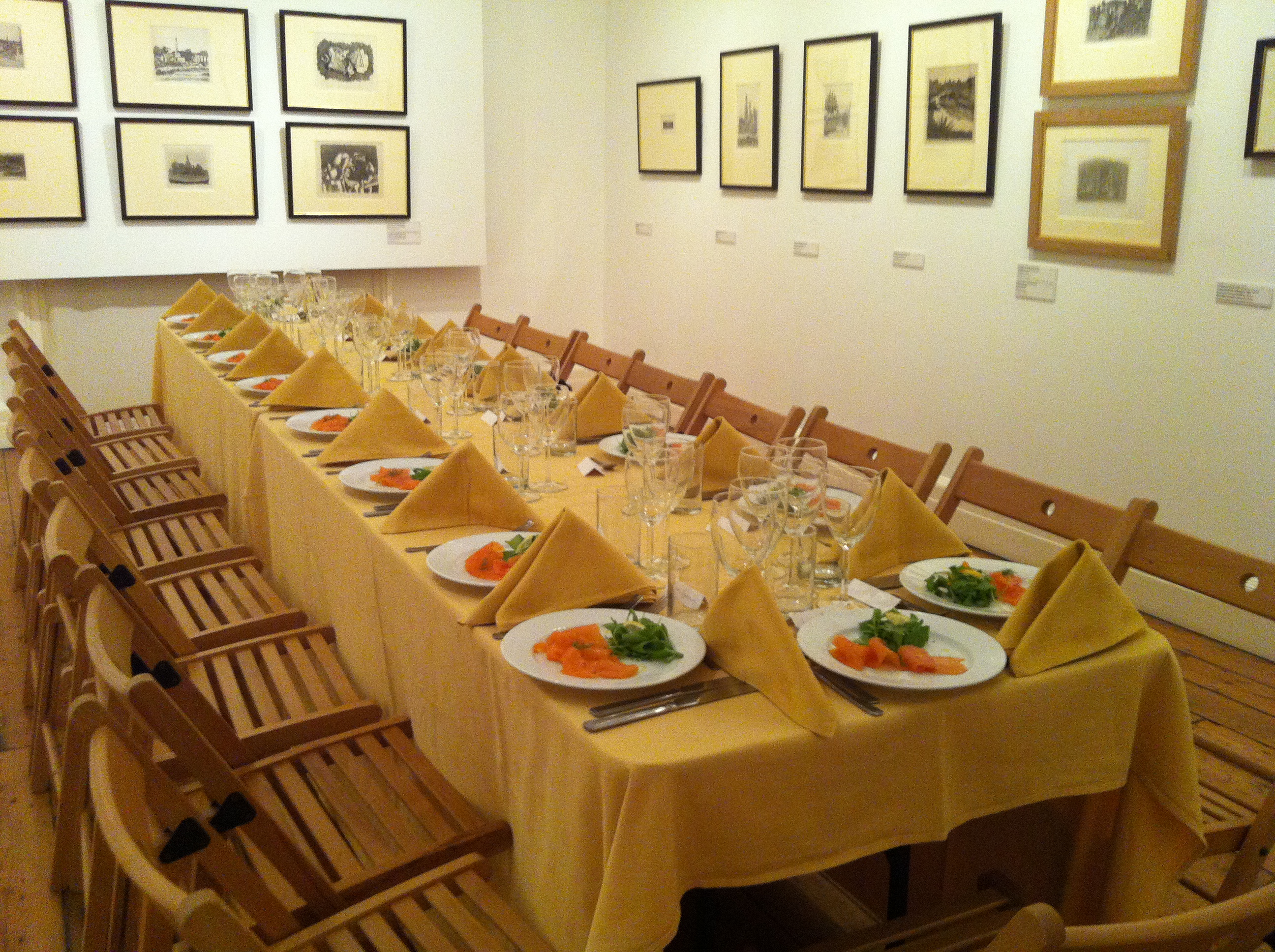 Elegant dining table setup with yellow tablecloth for corporate dinner in Estorick Collection.