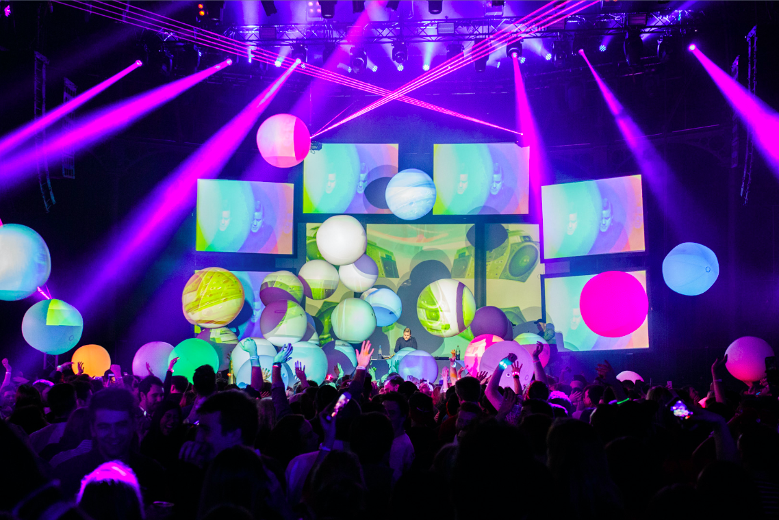 Vibrant Roundhouse event space with dynamic lighting and colorful projections.