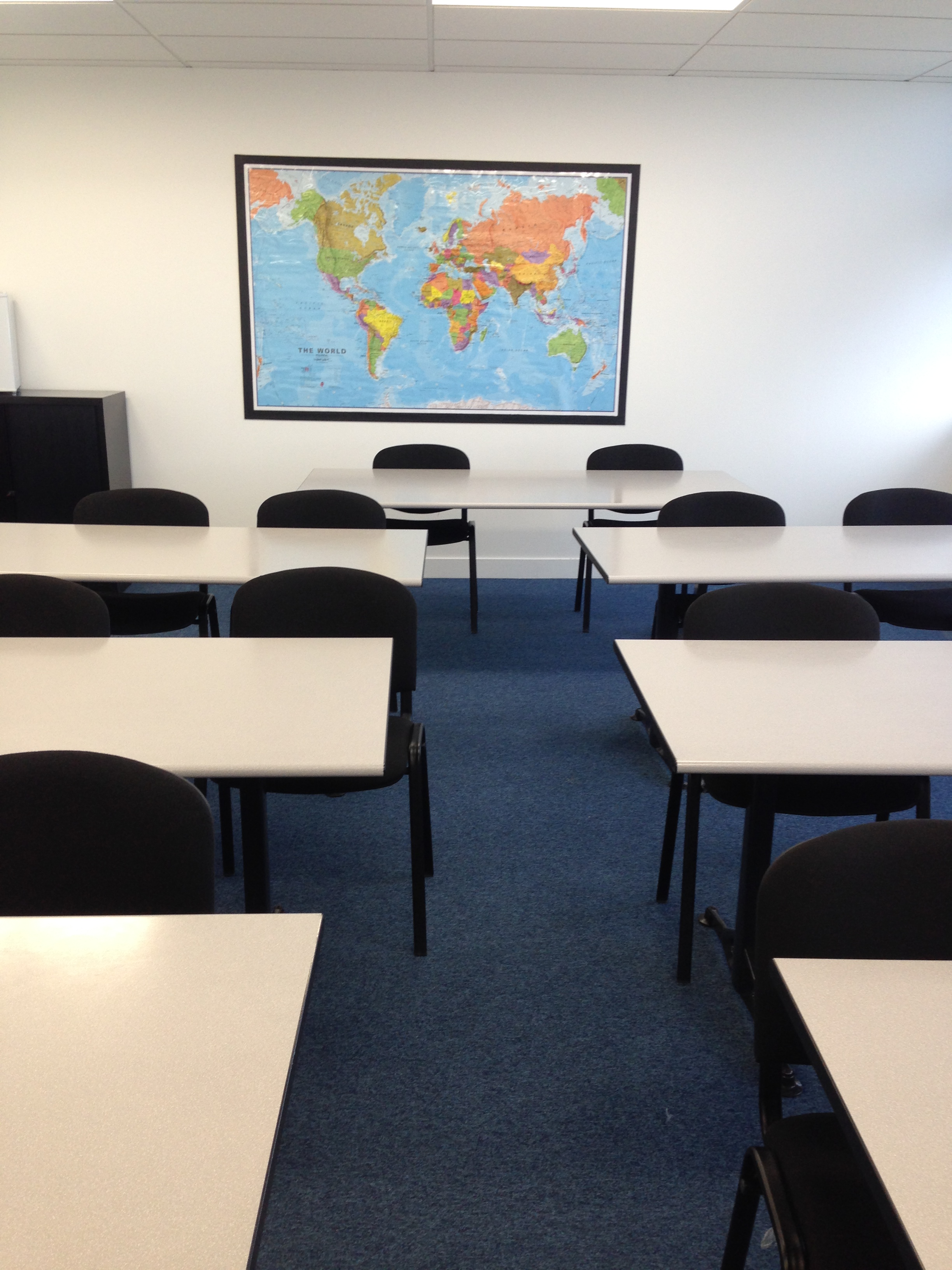 Training room with tables, chairs, and world map for workshops and meetings.