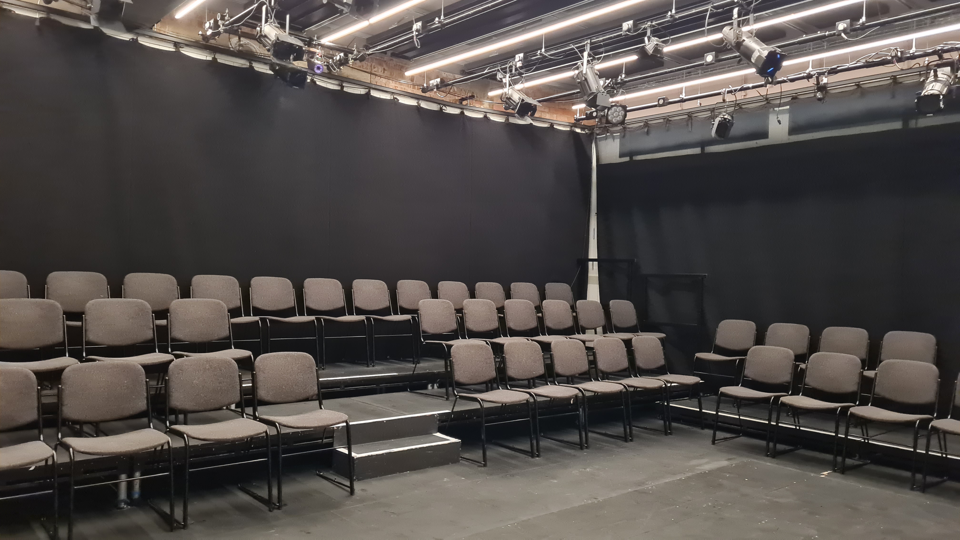 Versatile Bush Theatre studio with tiered seating for presentations and performances.