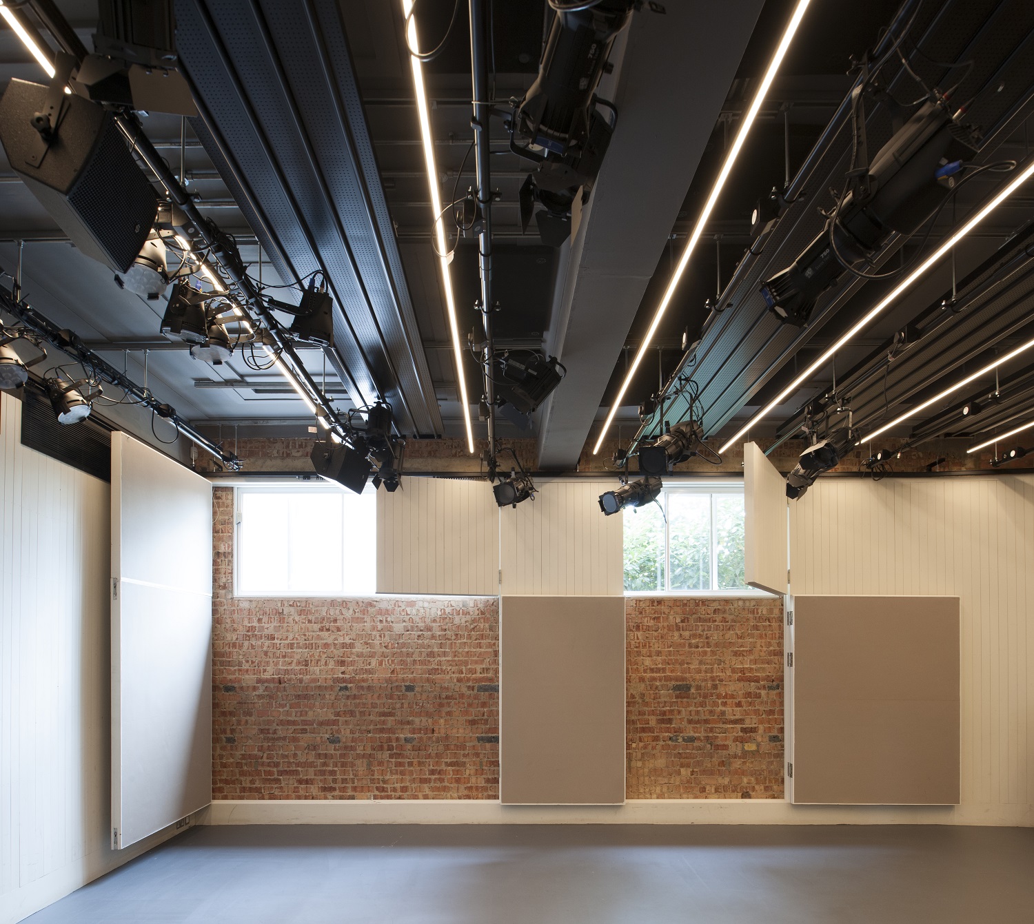 Versatile Bush Theatre studio with exposed brick walls for events and meetings.