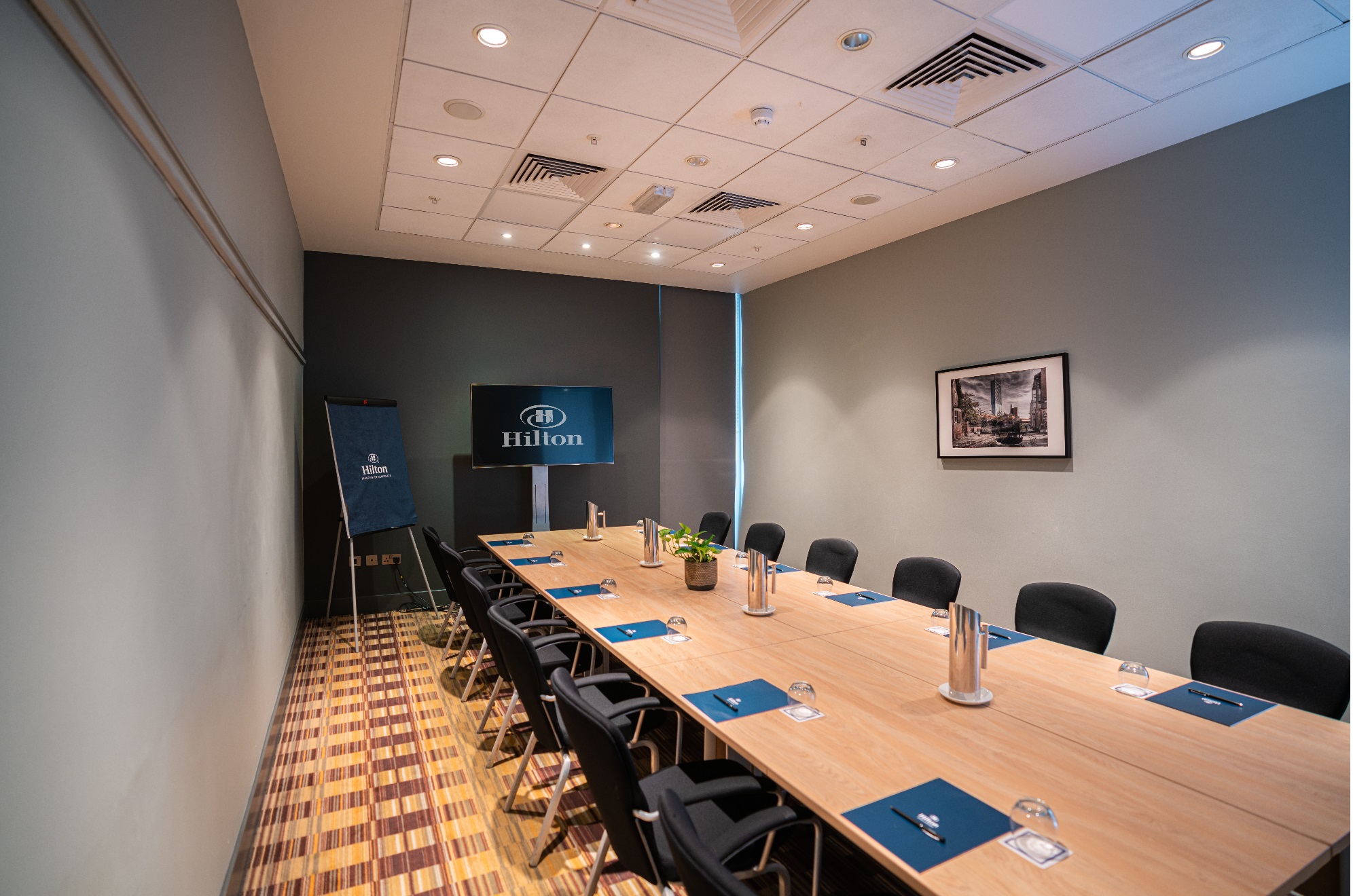 Boardroom at Hilton Deansgate with wooden table, ideal for corporate meetings and events.