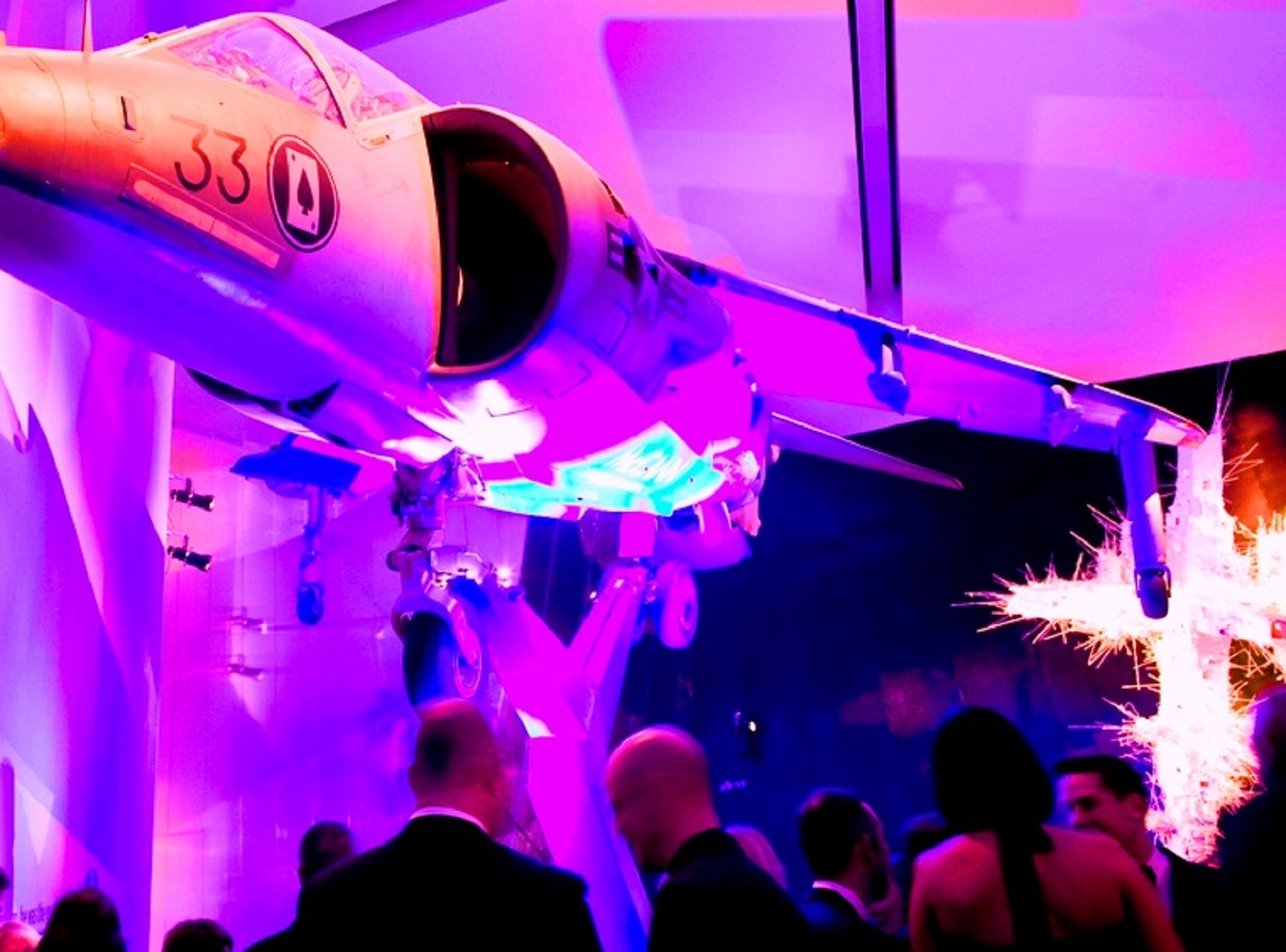 Exclusive Hire event space with aircraft installation and vibrant purple lighting.