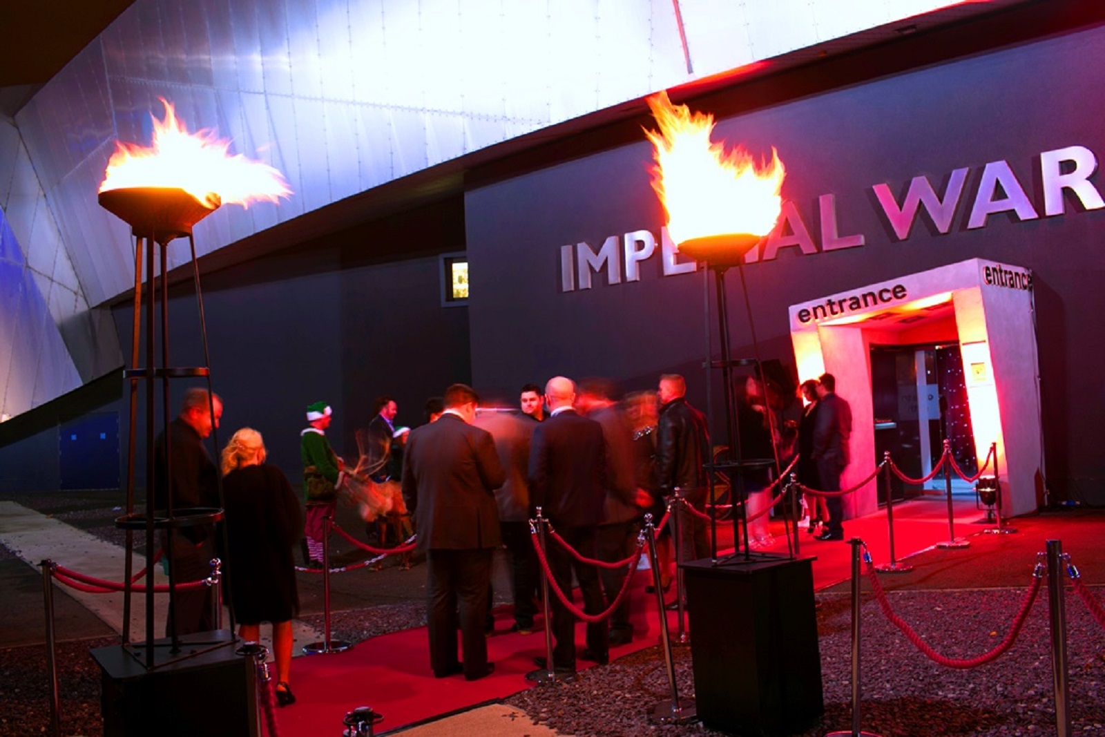 "Quayside entrance at Imperial War Museum North with red carpet and flame torches for upscale events."