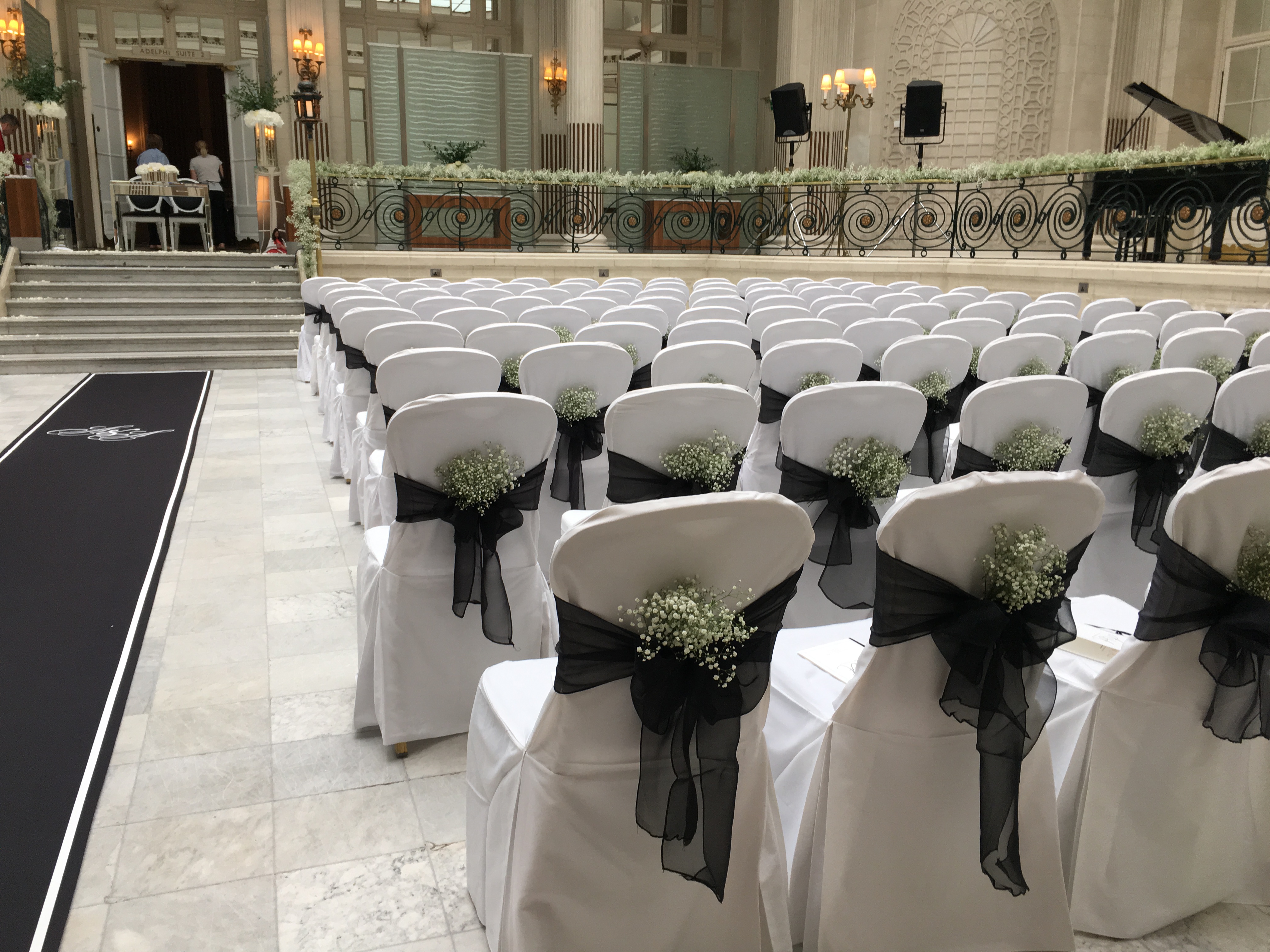 Elegant wedding setup in Palm Court, The Waldorf Hilton, with white chairs and floral accents.