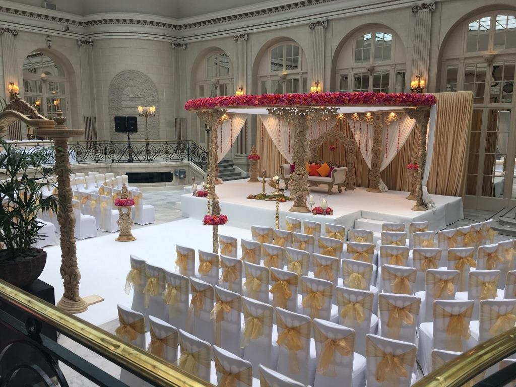 Elegant wedding venue at Palm Court, Waldorf Hilton, featuring floral decor and gold-accented chairs.
