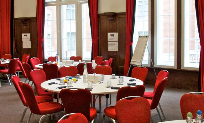 Council Chamber at Hallam Conference Centre with round tables and red chairs for meetings.