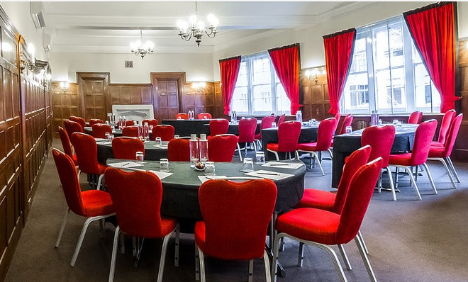 Oxford Suite meeting room with round tables, red chairs, ideal for workshops and events.