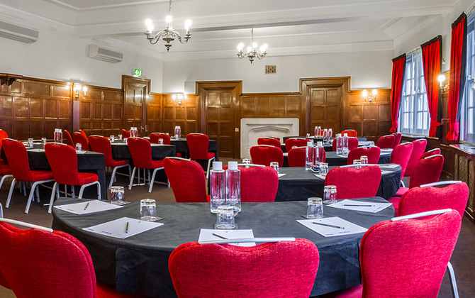 Oxford Suite meeting room with round tables and red chairs, ideal for corporate events.