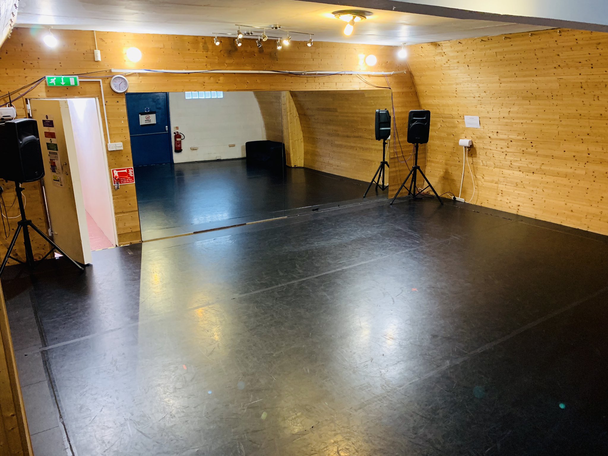 Dance school event space with wooden walls, polished floor, ideal for workshops and performances.