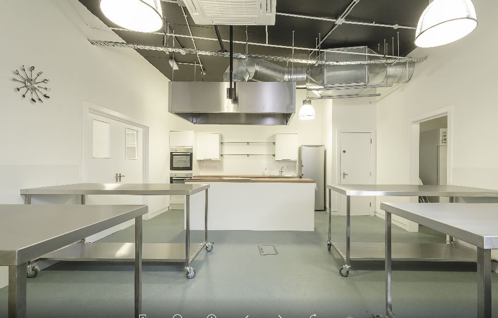 Modern kitchen space with stainless steel tables for culinary events and cooking classes.
